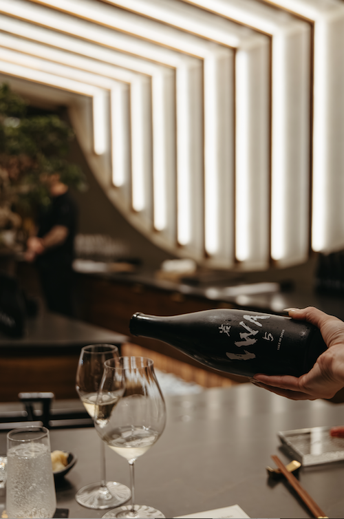 Pouring IWA 5 sake at the chef's counter during a Michelin-starred omakase pairing experience at Kōsen in Tampa, FL.