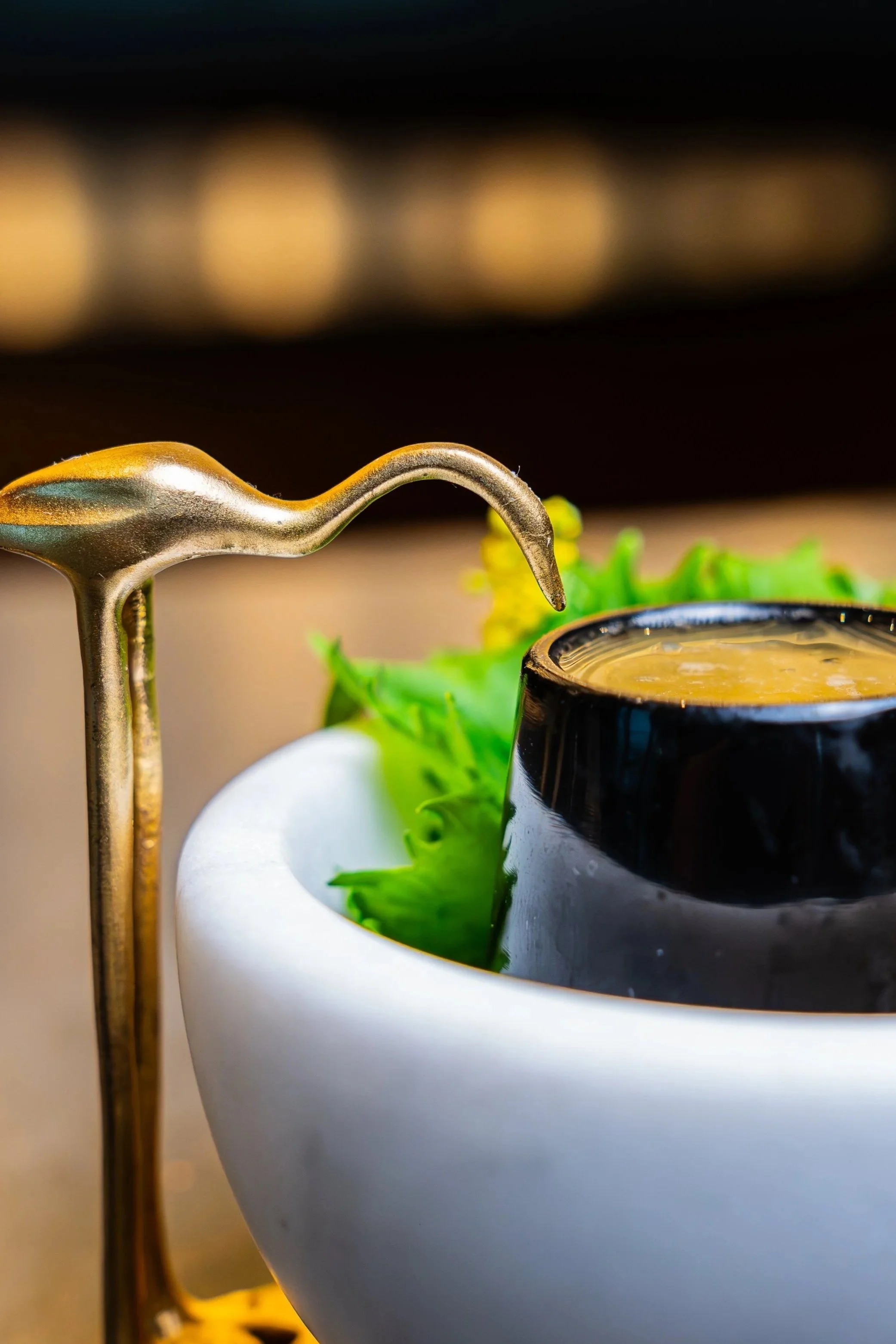 A close-up of a minimalist table setting at Kōsen in Tampa. A pair of dark wooden chopsticks rests on a slender, textured black ceramic chopstick rest.