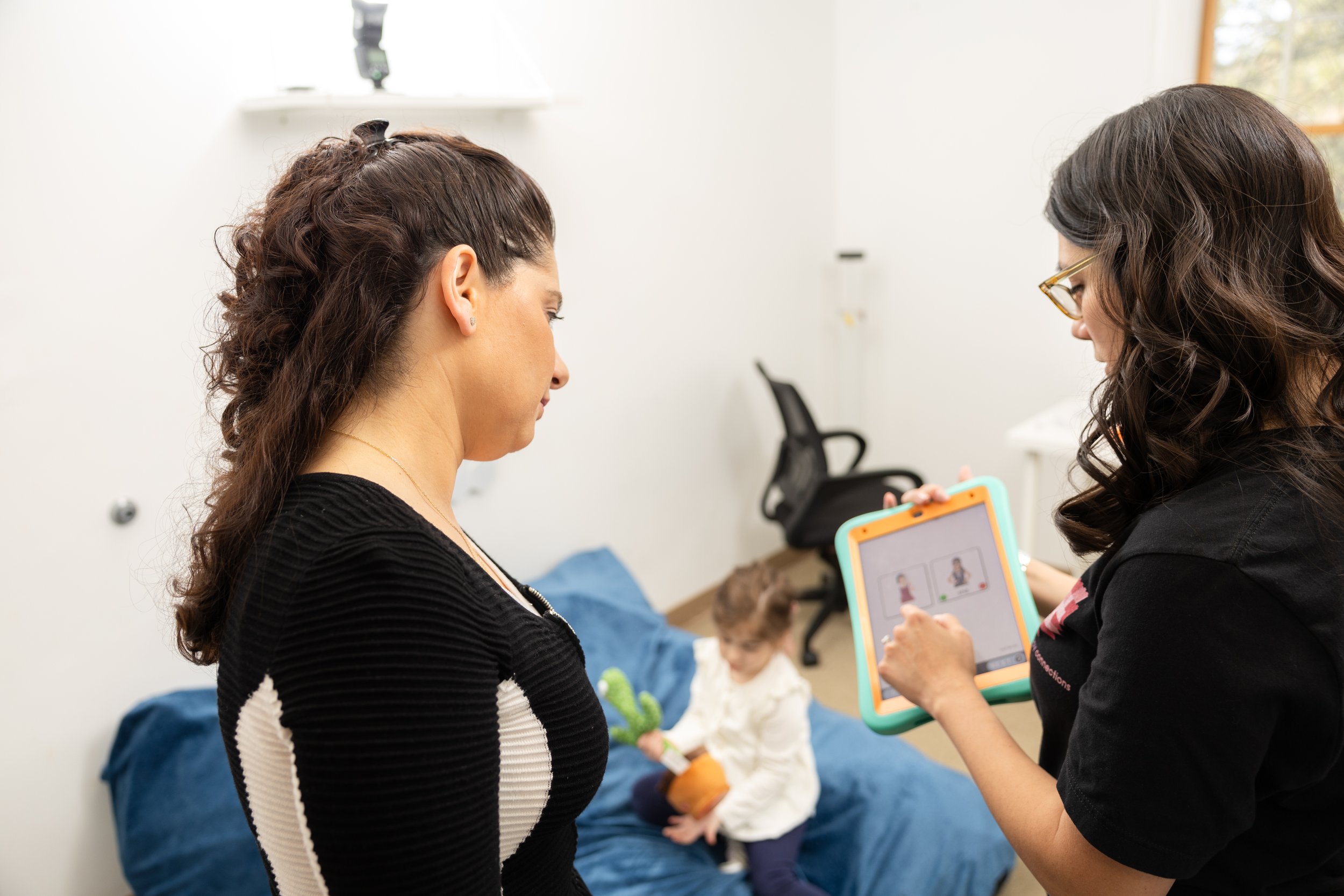 Pediatric Speech Therapist in Bergen Country New Jersey modeling AAC use with a caregiver