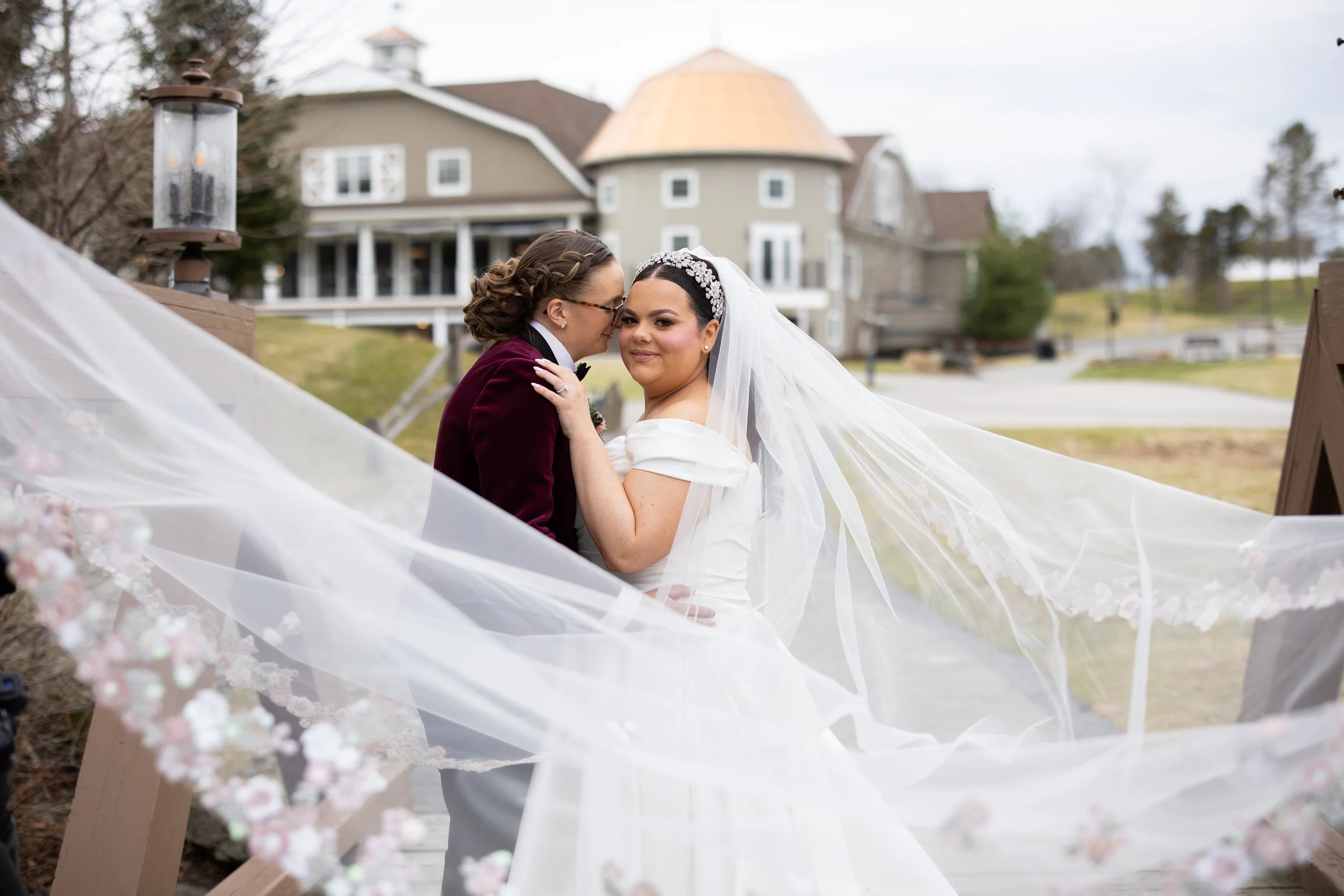 bride & bride getting a portrait taken on a bridge before their wedding