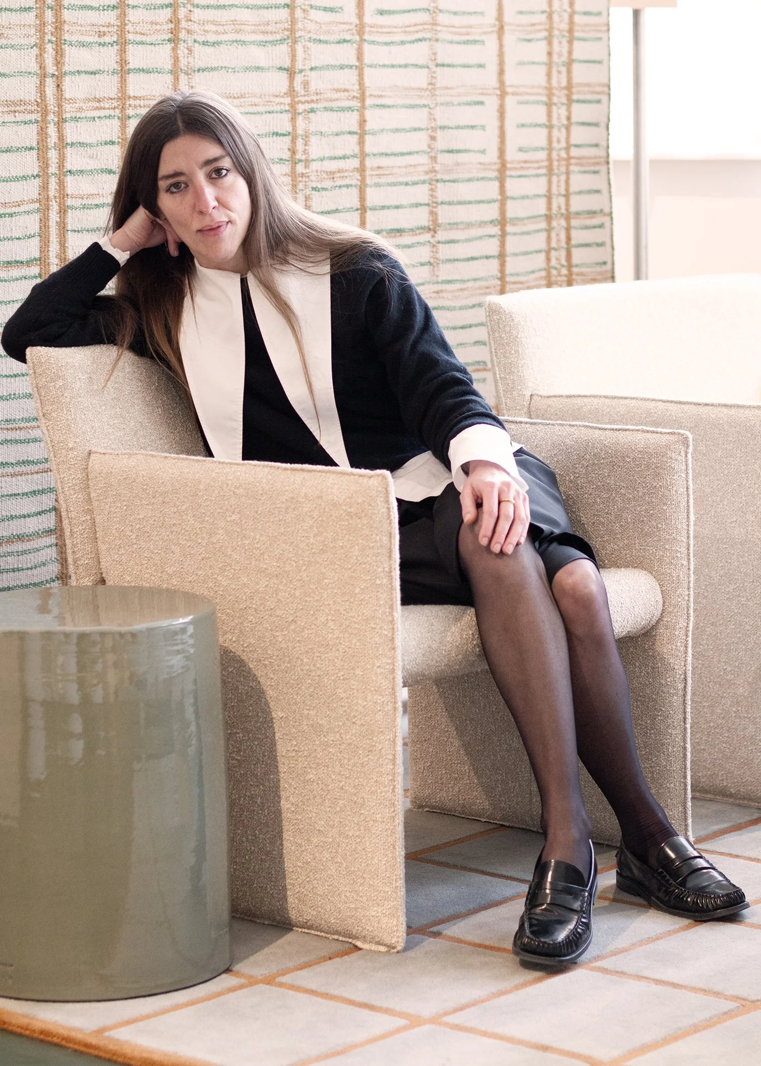 A flat lay of interior design materials including two large rugs, fabric swatches, paint color samples, paint sample tubes, a dried botanical, and sample photographs arranged on a white surface.