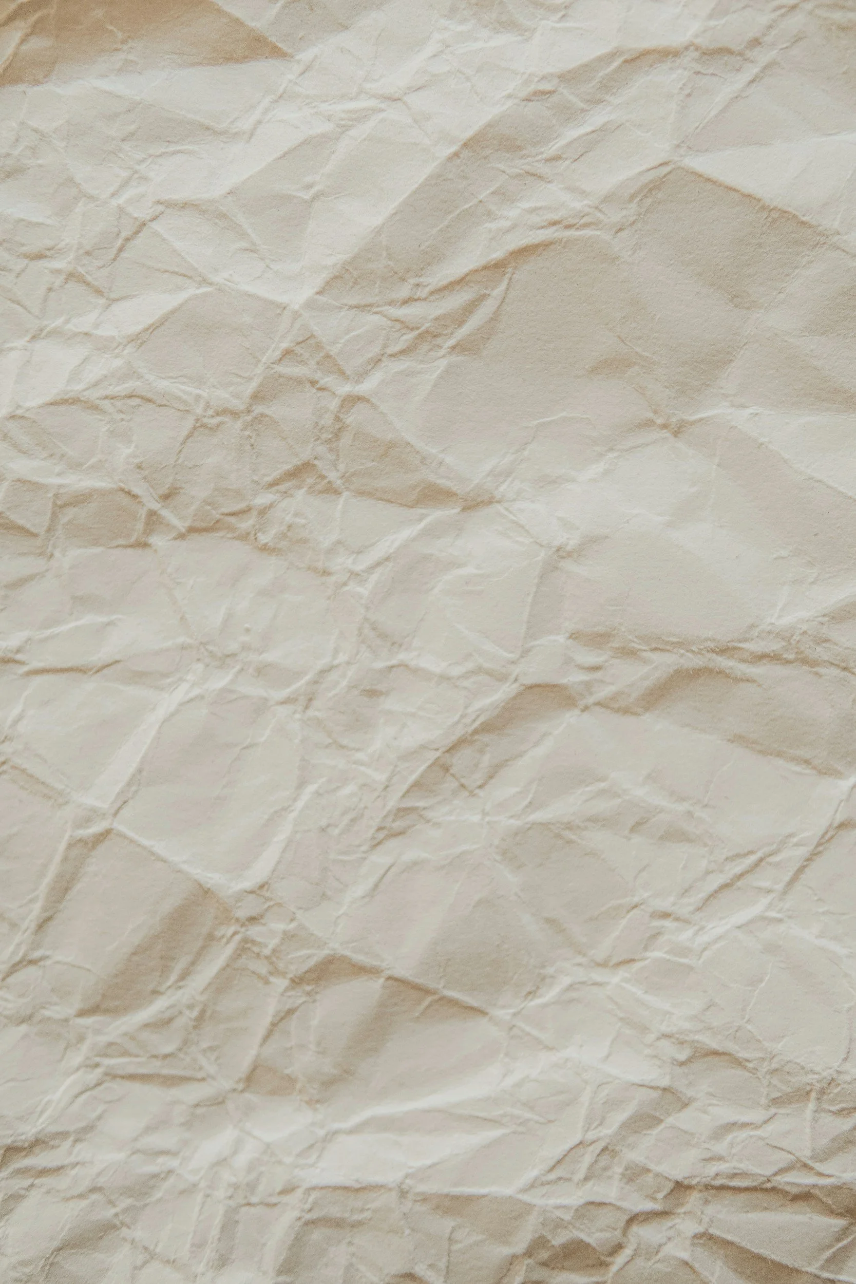 Close-up image of crumpled, beige paper with textured, wrinkled surface.