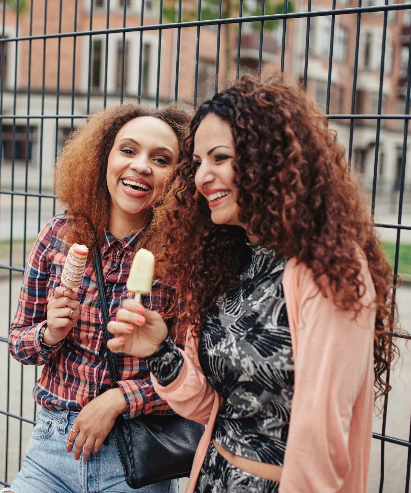 Two female friends smiling while eating popsicles