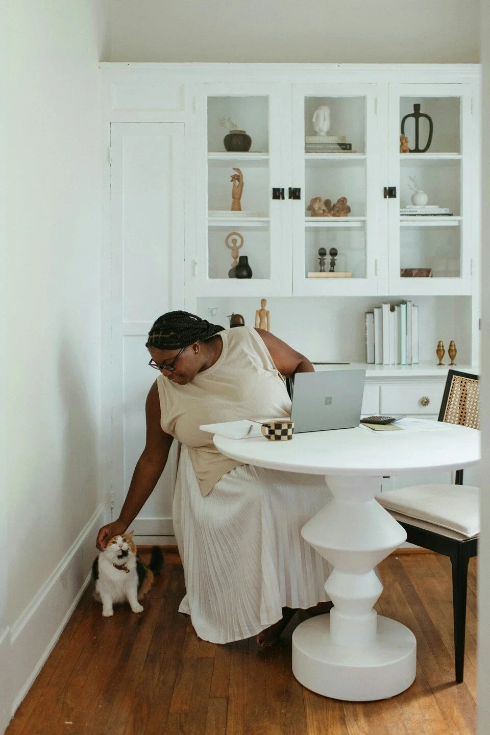 woman petting her cat while working on her laptop