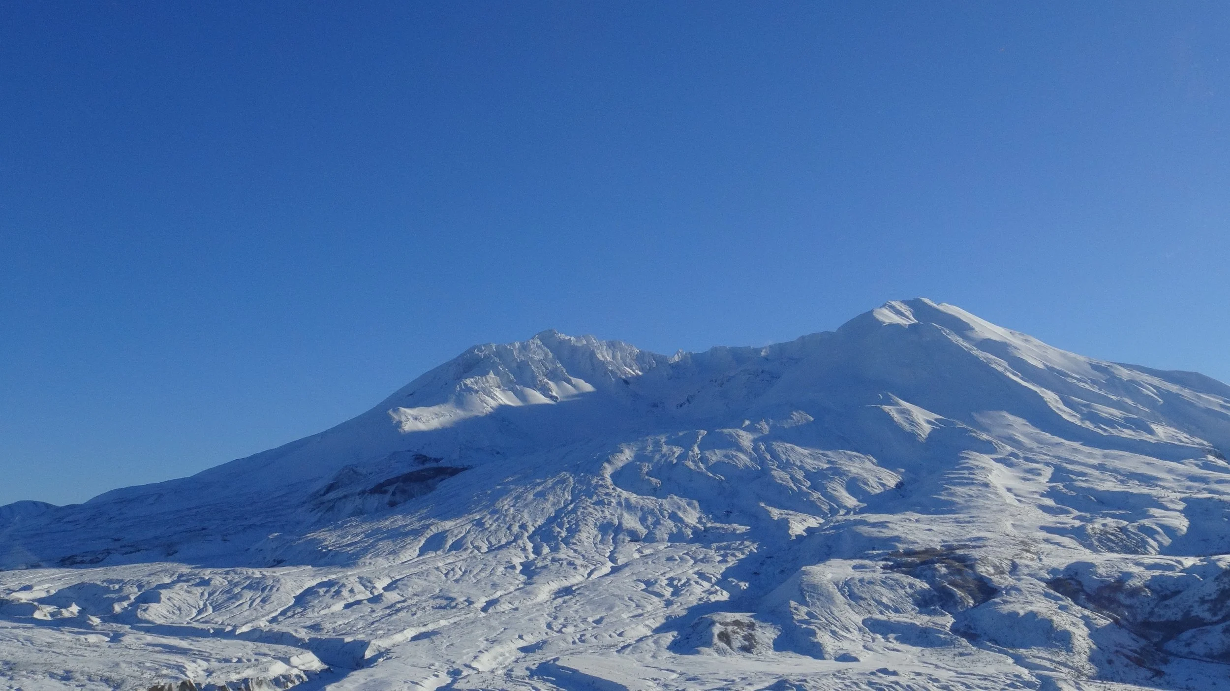 Snow-covered mountain under clear blue sky