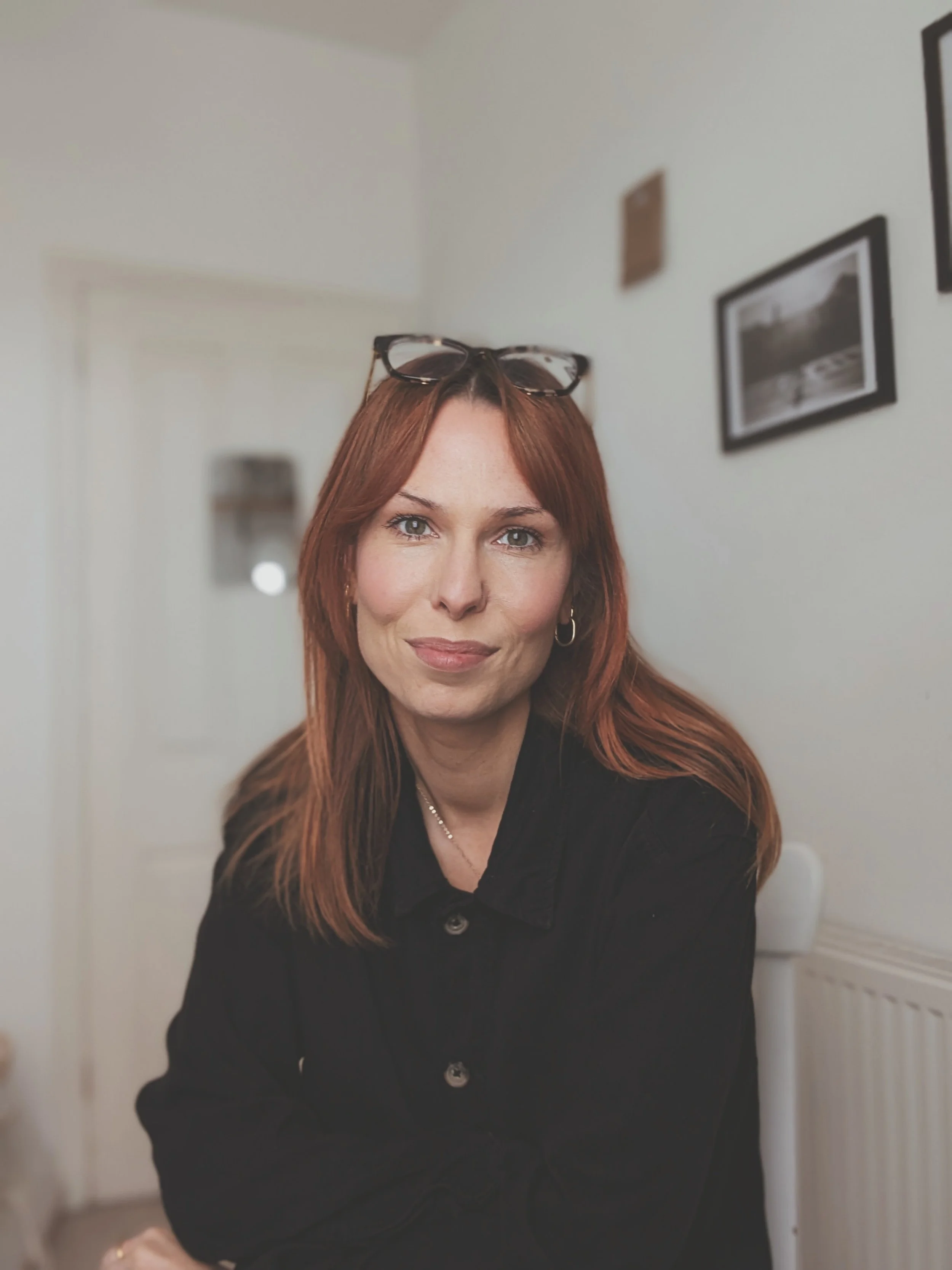 copywriter headshot, girl with red hair wearing black shirt - glasses on head