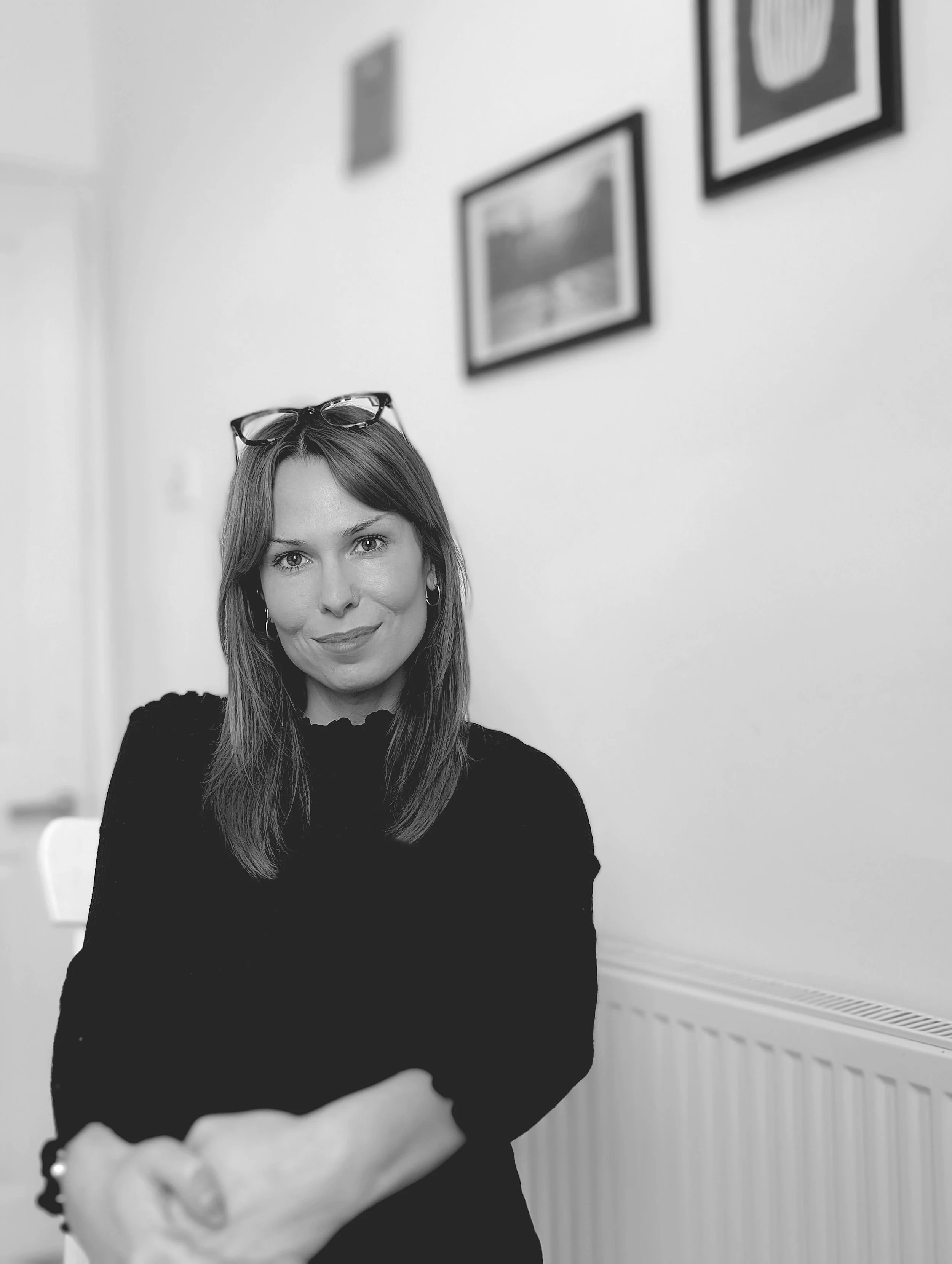 girl in black top with glasses on head - black and white headshot