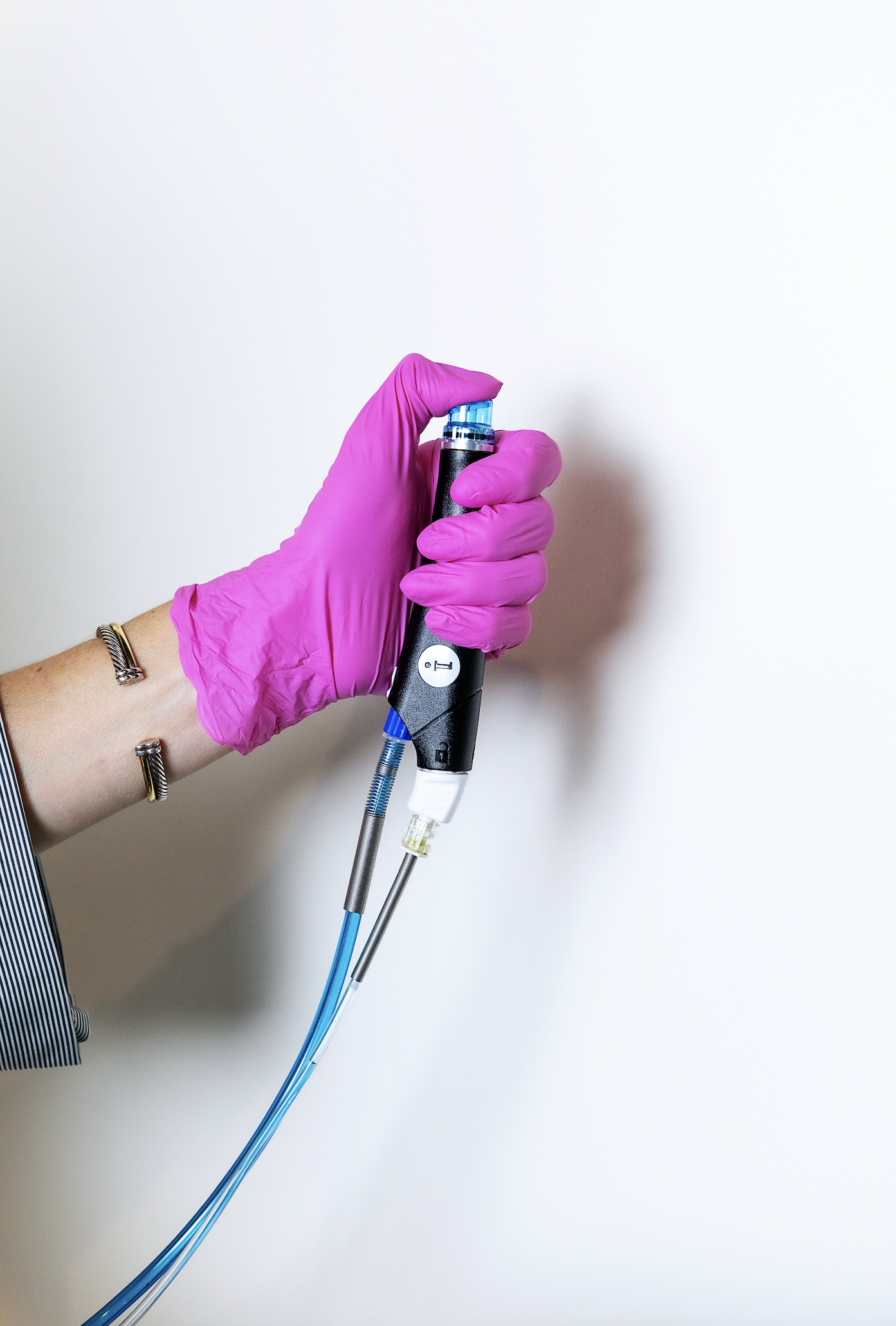 Person wearing pink gloves holding a medical tool against a white background.