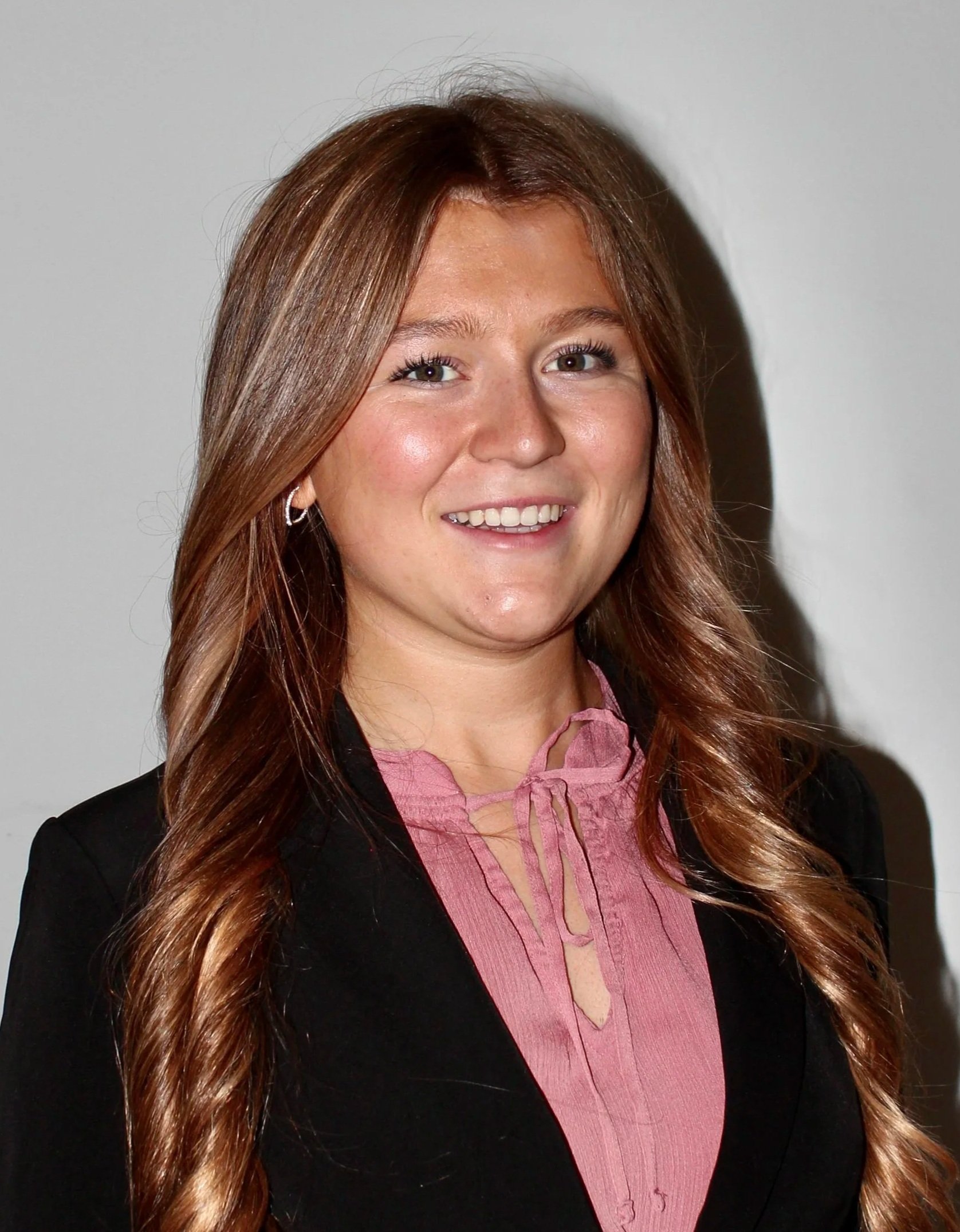 A young girl smiling with long blonde-brown hair