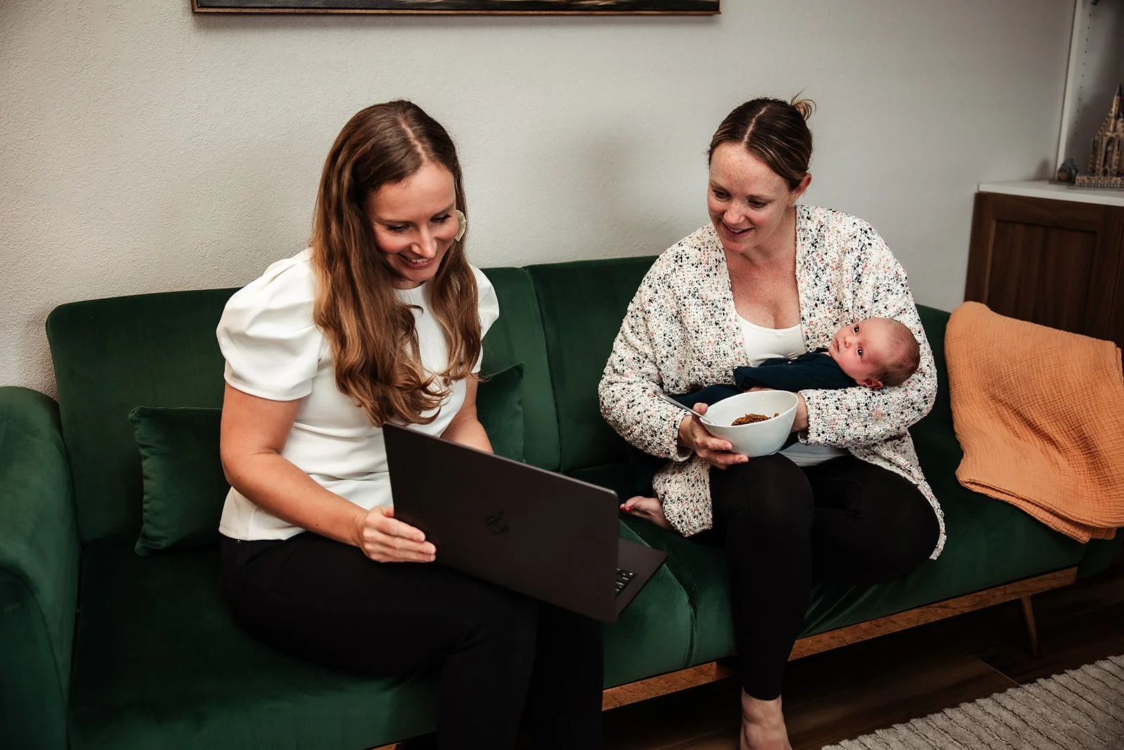 Karina Wenker, Nutritionist, sitting on the couch with a postpartum mother holding a newborn, guiding her through her postpartum nutrition plan