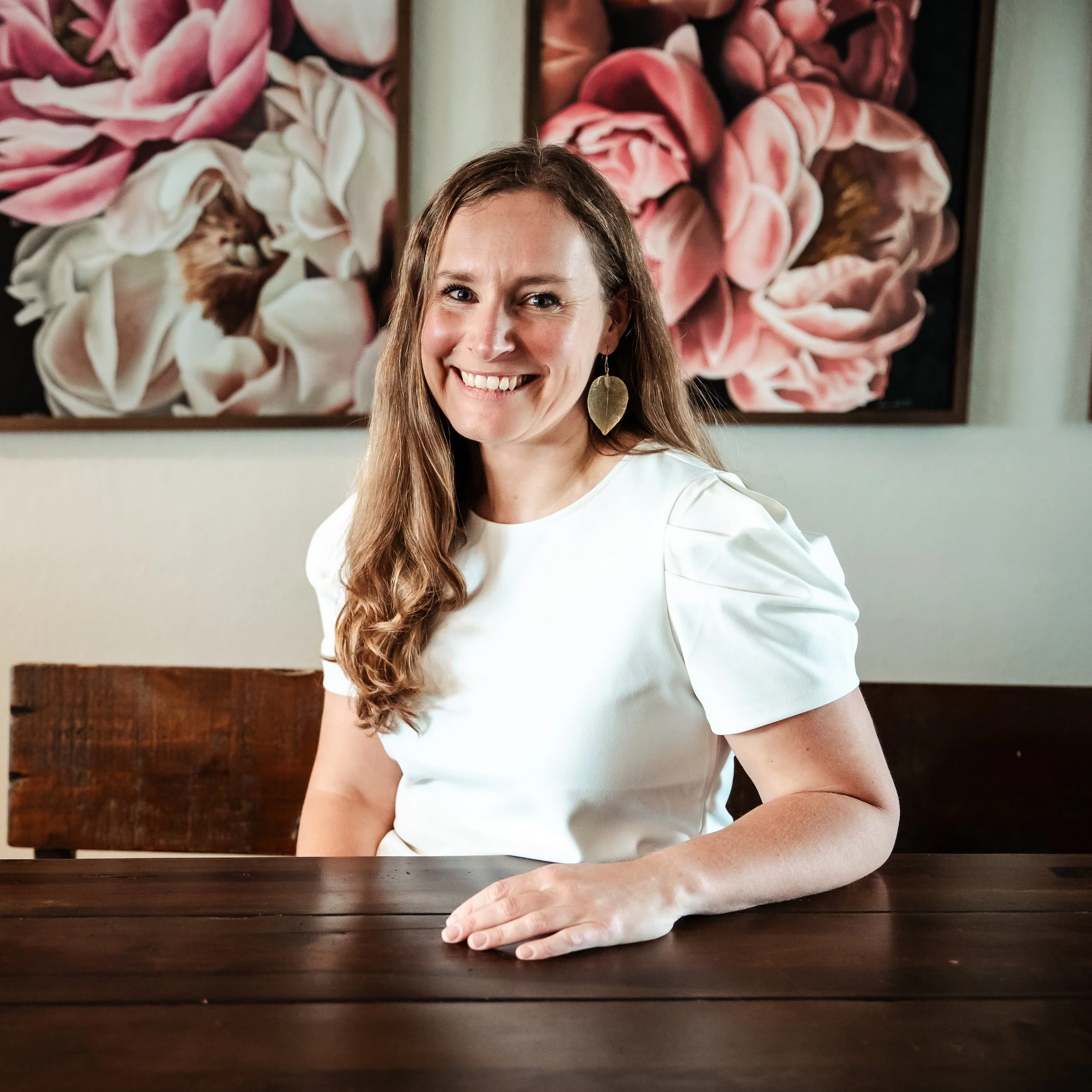 Nutritionist Karina Wenker is sitting at a table, hand on the table, smiling at you