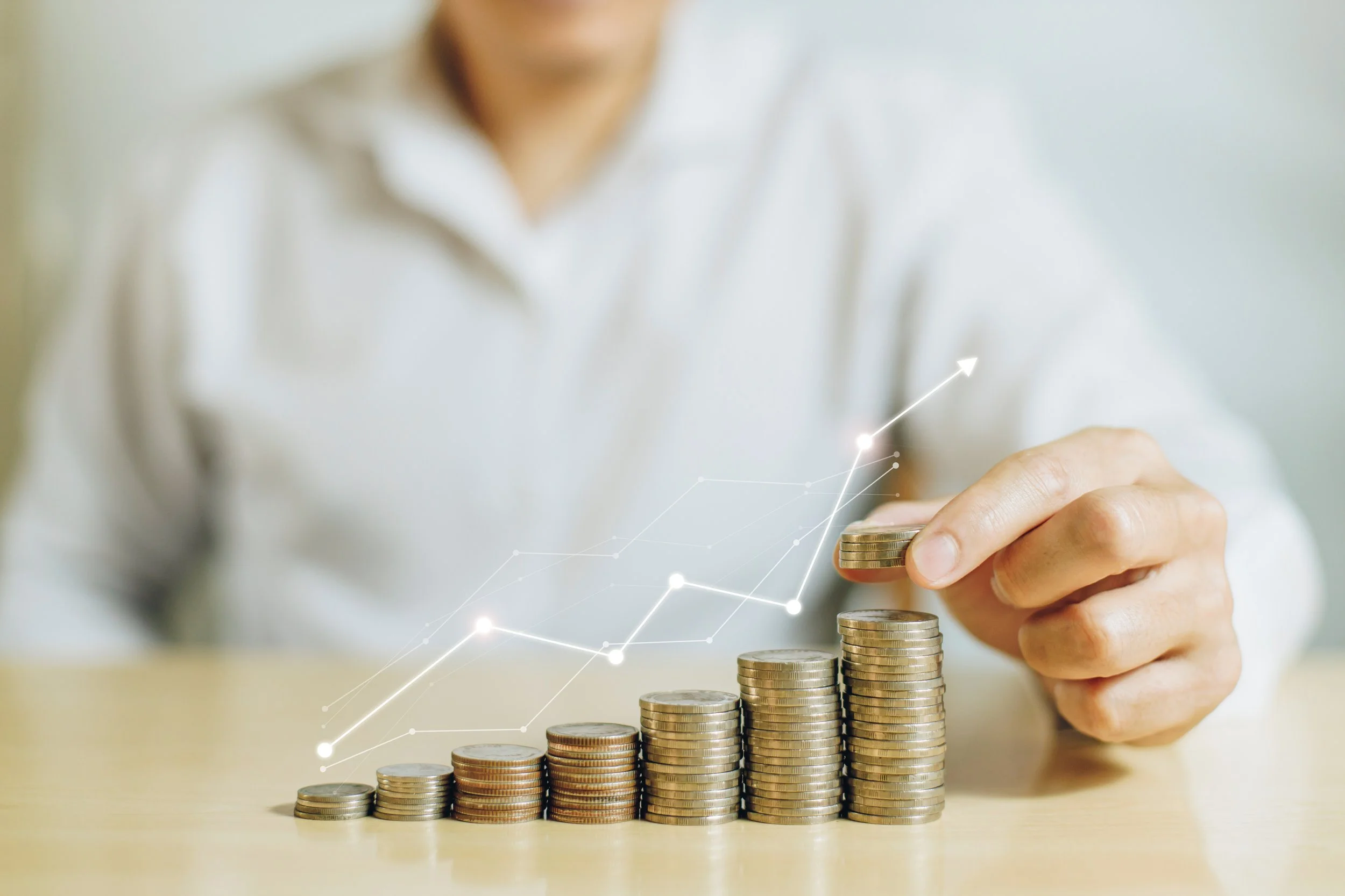 Person stacking coins in increasing order with a digital line graph indicating growth.