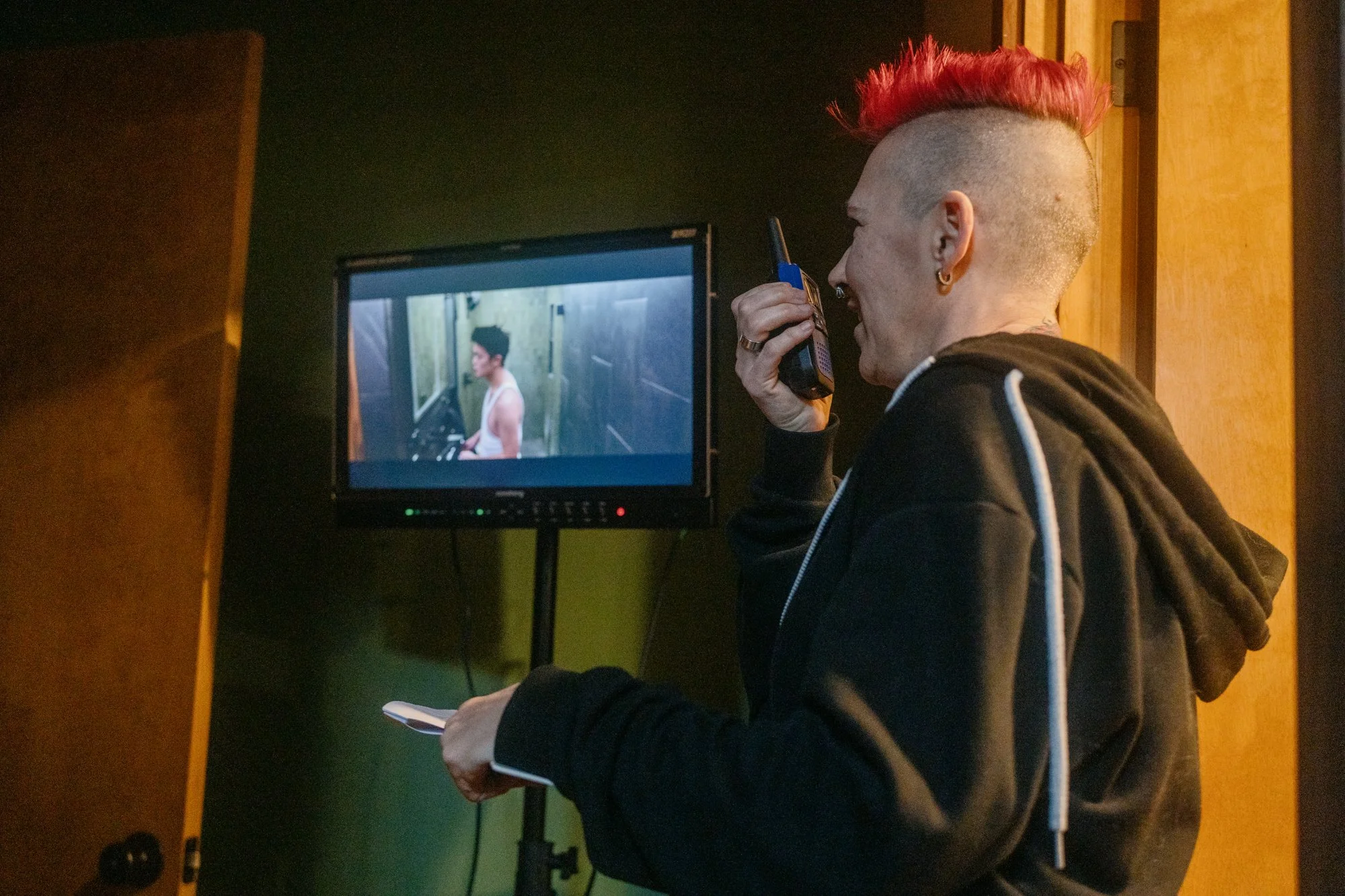 Ren uses a walkie to ask for quiet on set while shooting "Leo" in a small space