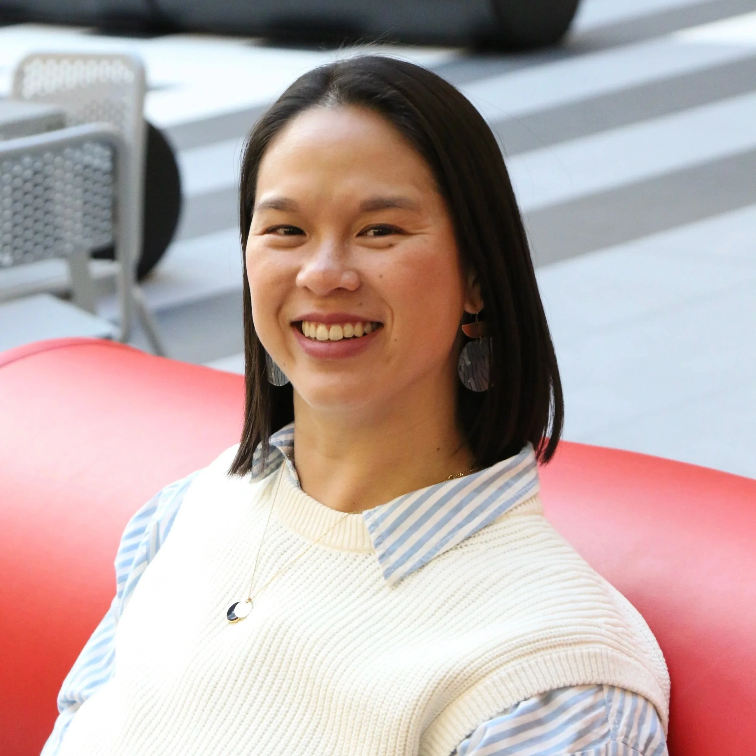 Gloria Julien, life and career coach, smiling in a room with empty chairs — likely before or after a speaking event or workshop.