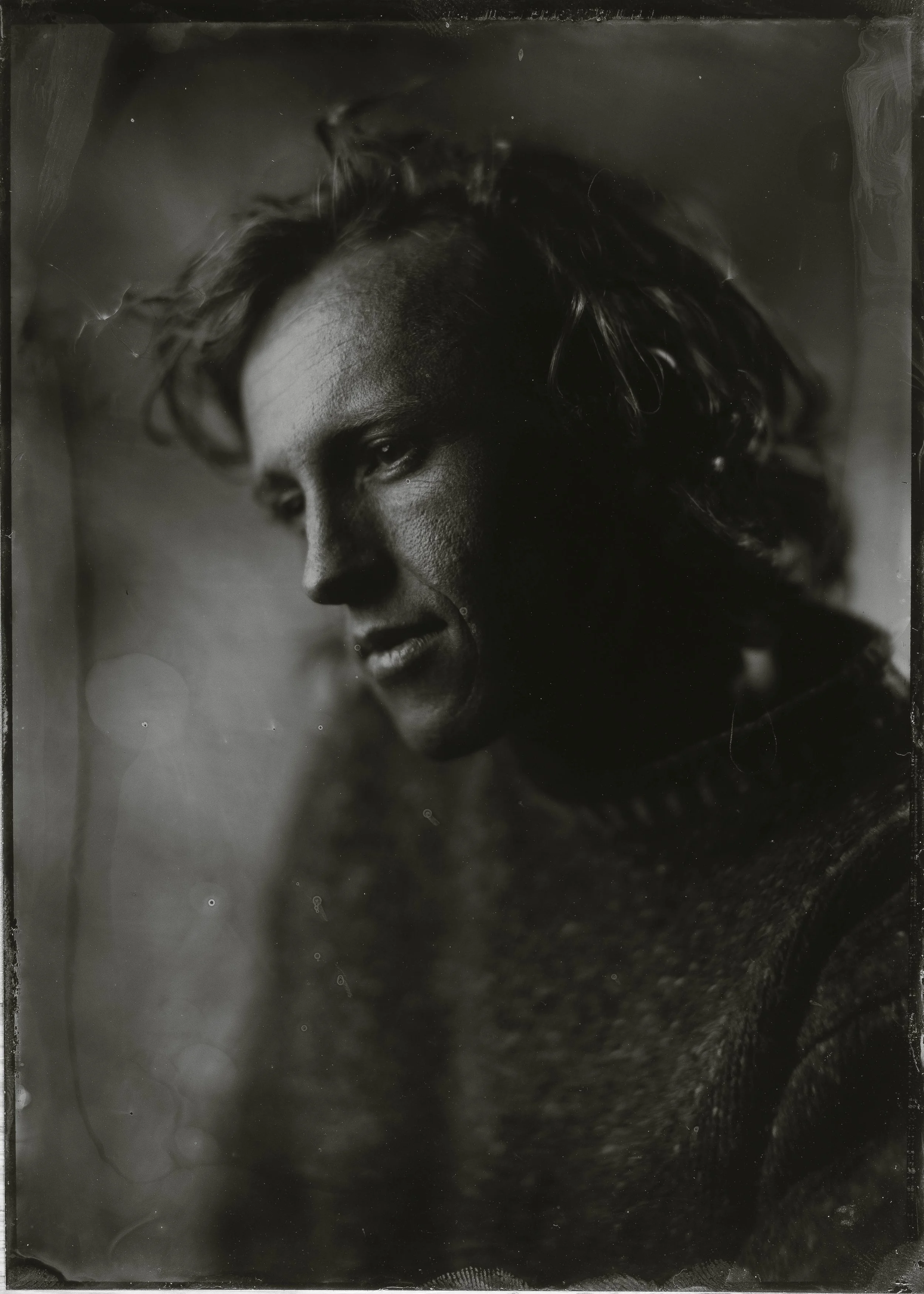 Black and white portrait of a woman with short wavy hair, looking downward with a thoughtful expression.