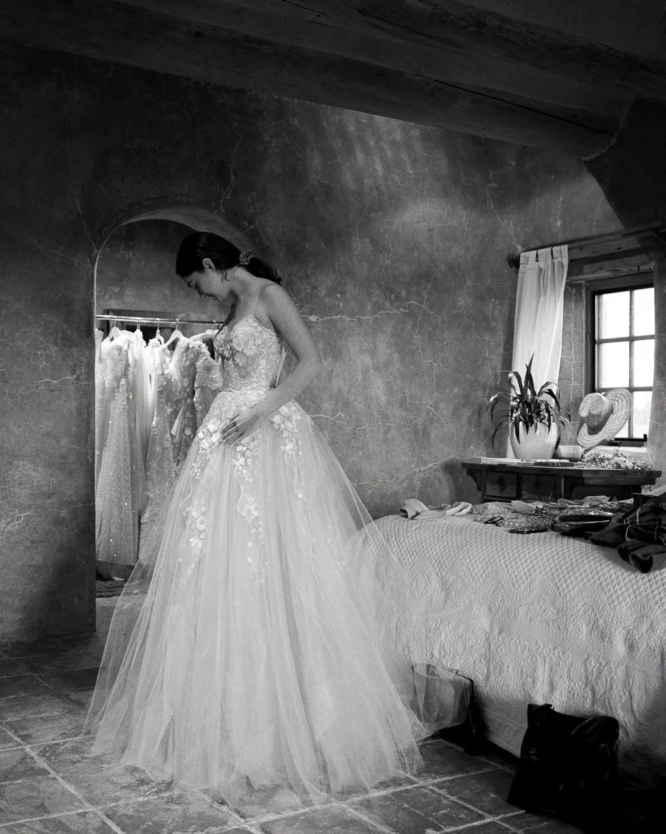 Black and white photo of a bride being fitted for a wedding dress.