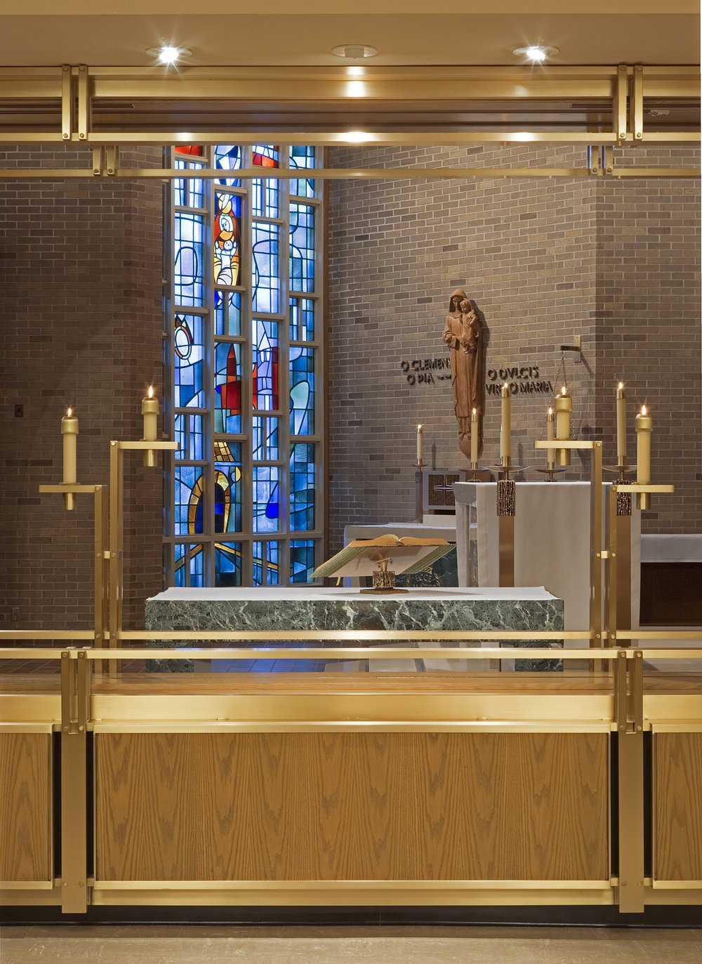 Integrated into the bronze sculptural framework and flanking the side altar are two candleholders, reflecting the abstracted form of wheat.