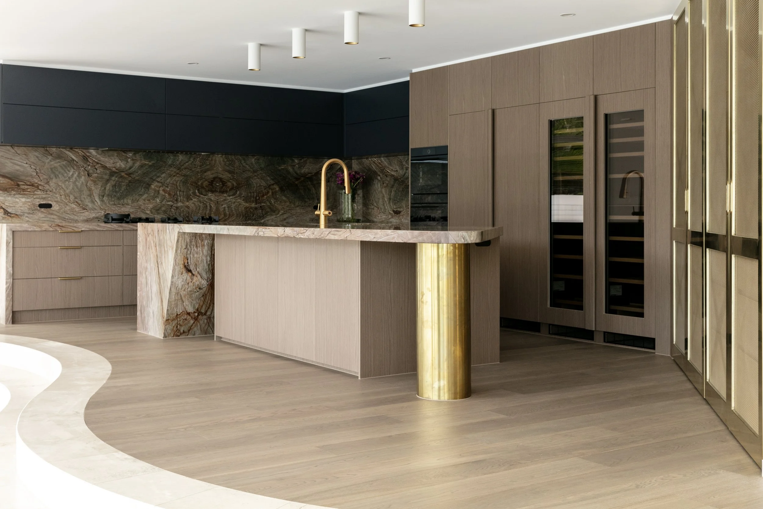Wyuna, a renovated kitchen in Noosa Heads with a marble waterfall island, timber joinery and brass tapware