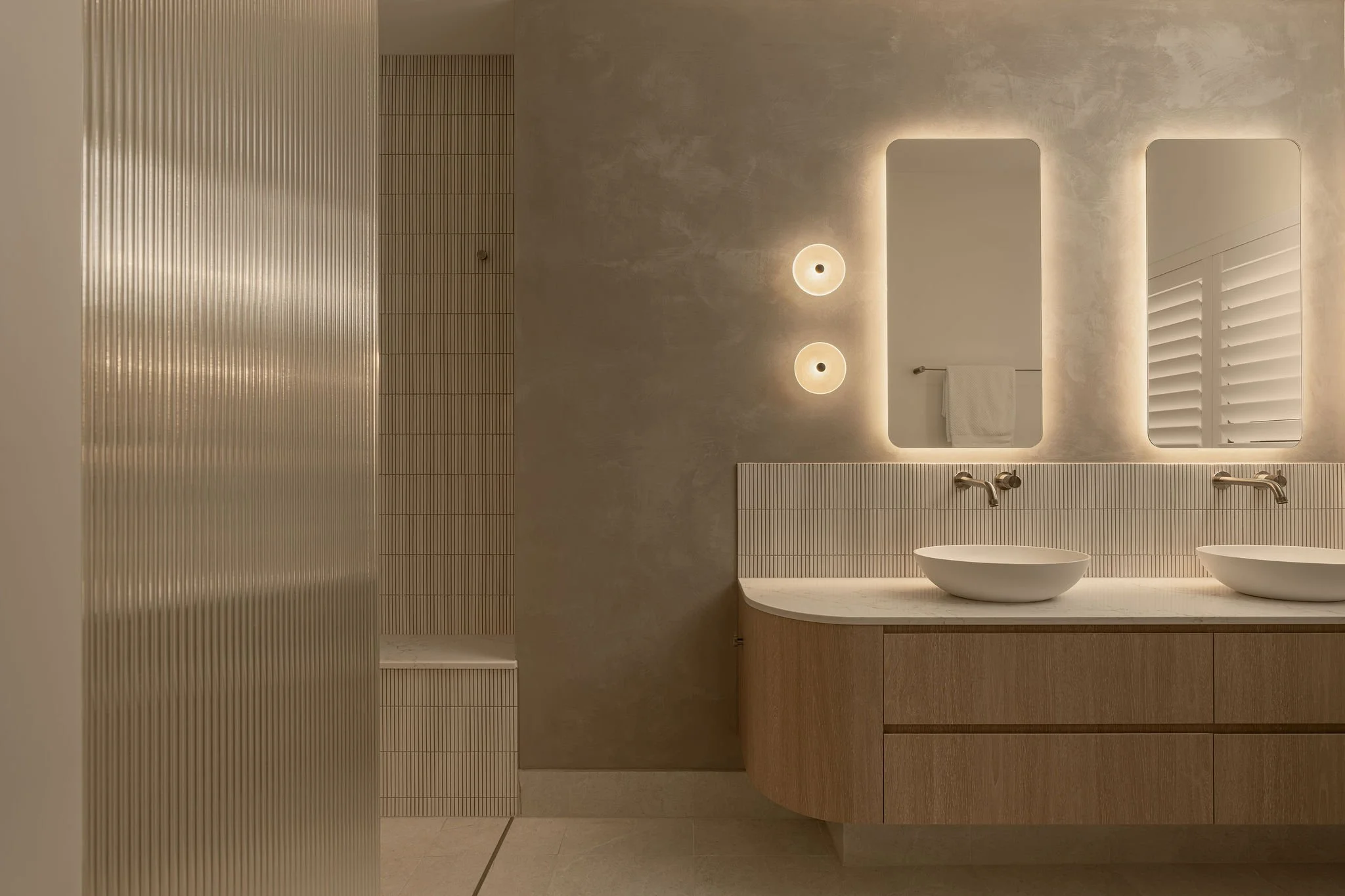 Sunshine Retreat, twin stone basins on a curved timber vanity beneath backlit mirrors and finger tile splashback