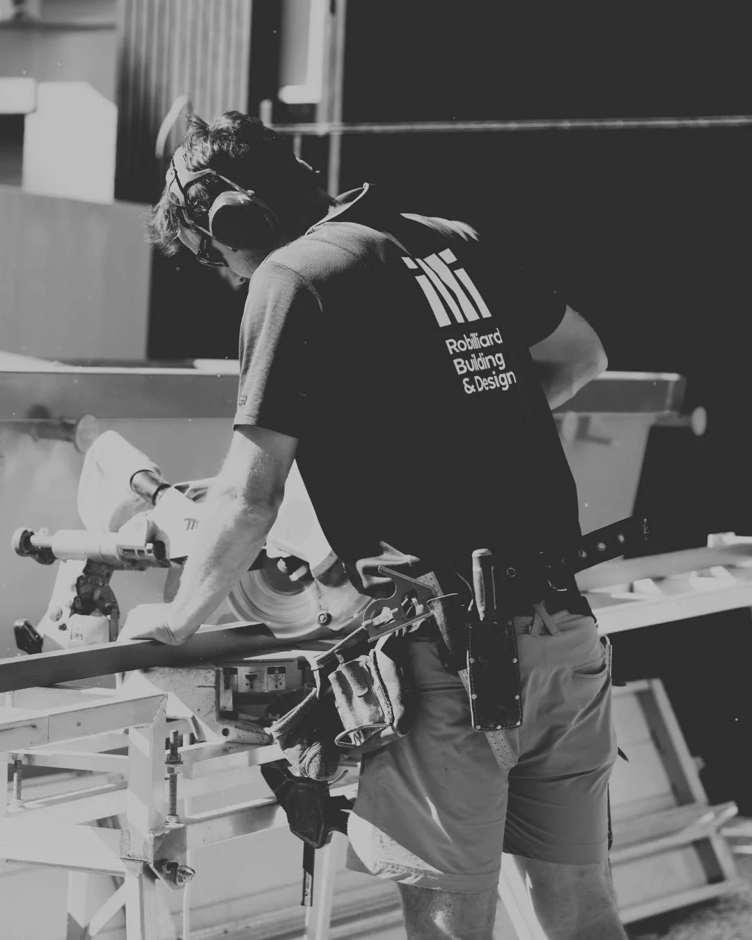 A Robilliard Building & Design carpenter in a branded shirt cutting timber on site