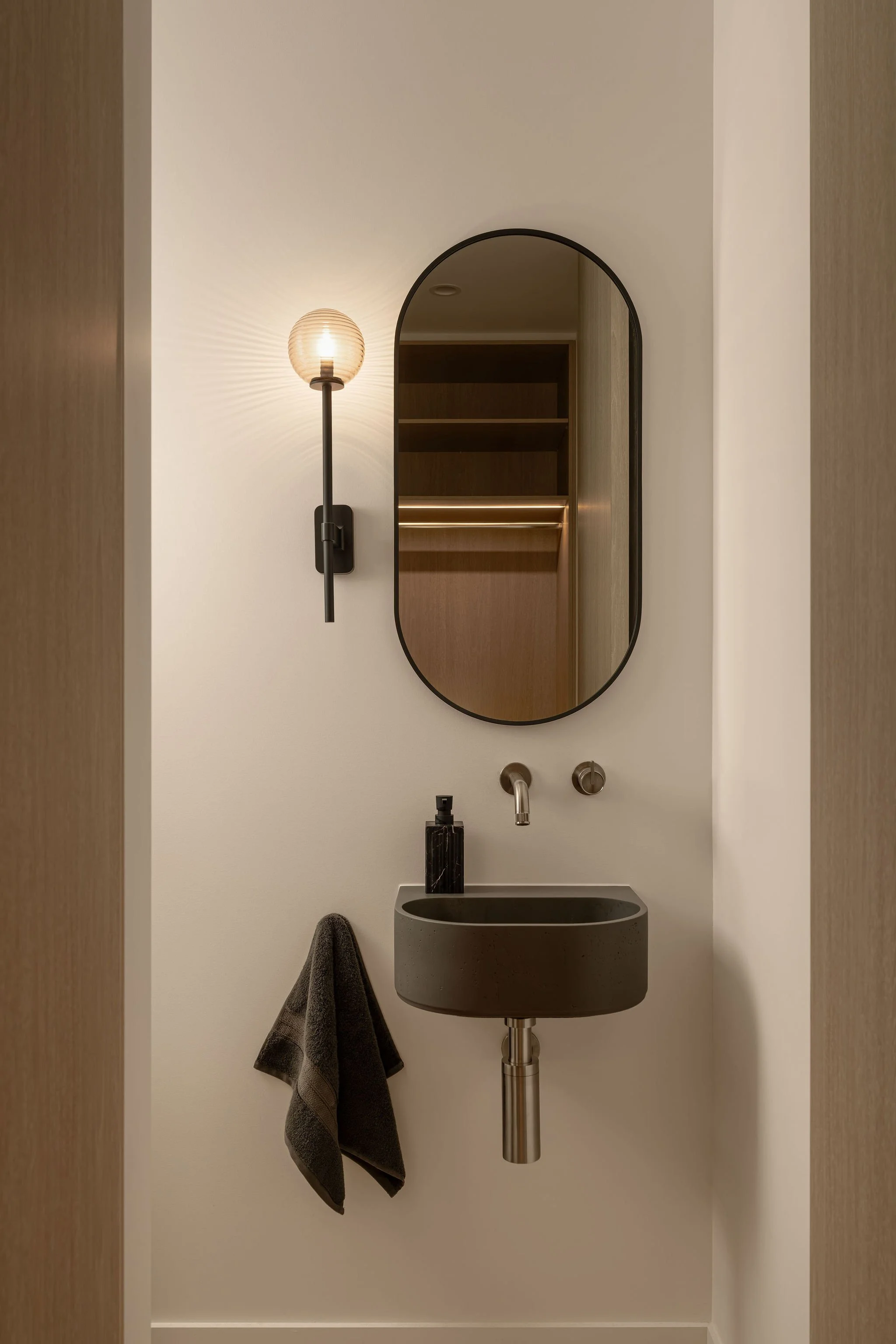Sunshine Retreat, powder room with oval black-framed mirror, wall light and dark grey wall-hung basin