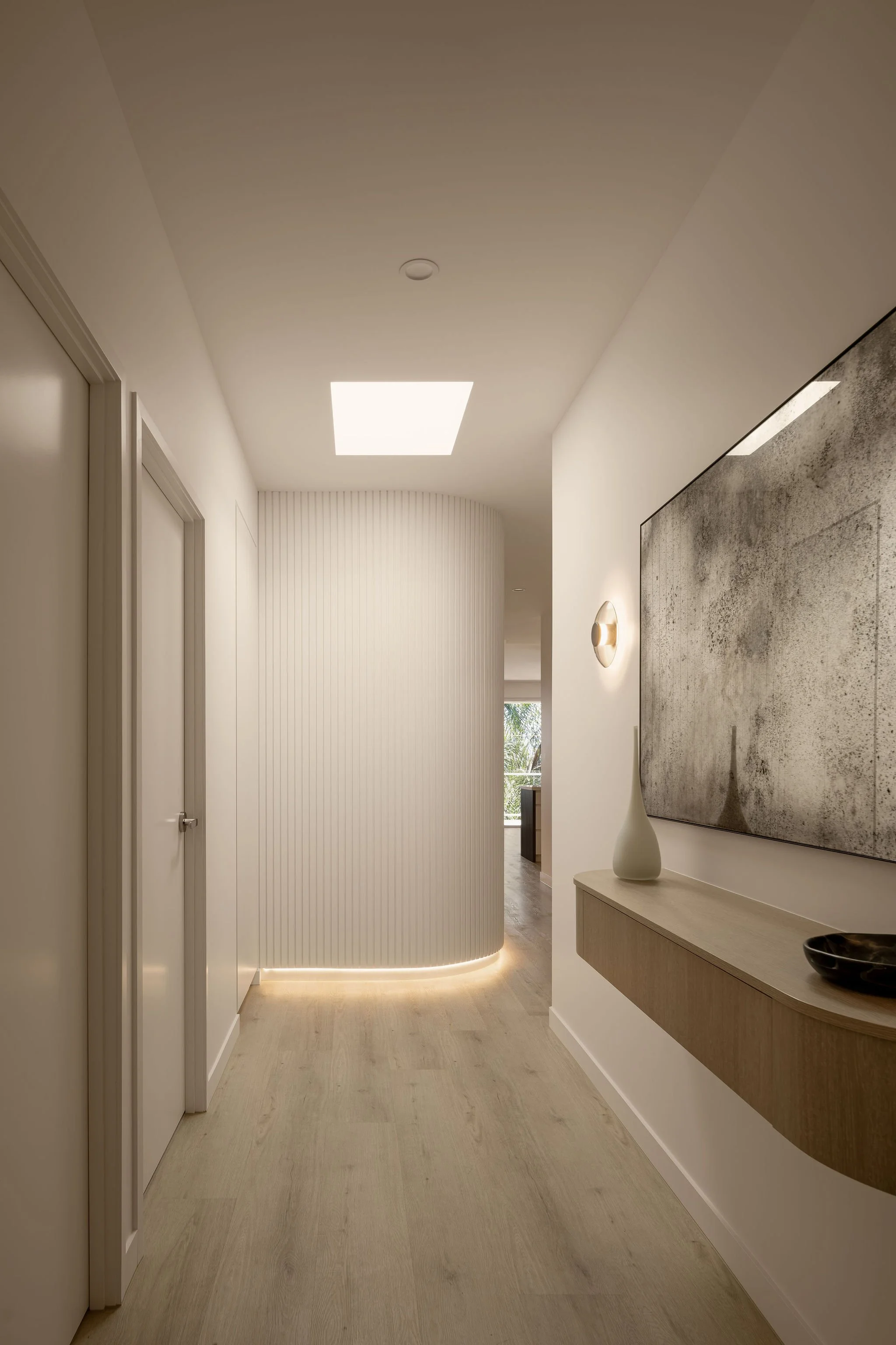 Sunshine Retreat, hallway with curved fluted wall, concealed strip lighting, skylight and floating timber console