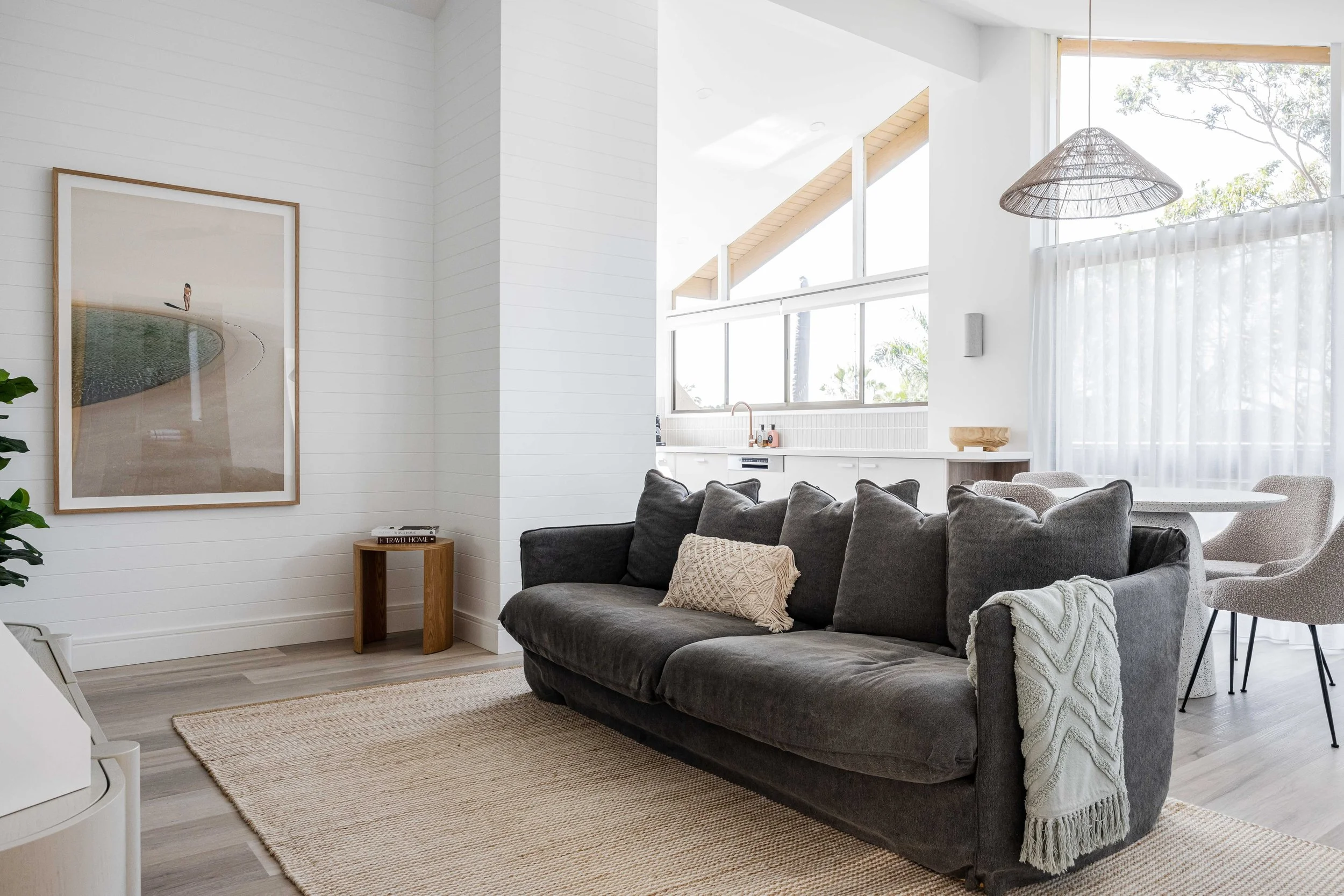 Otto, a renovated eighties unit in Noosa Heads with white panelled walls and a deep grey sofa
