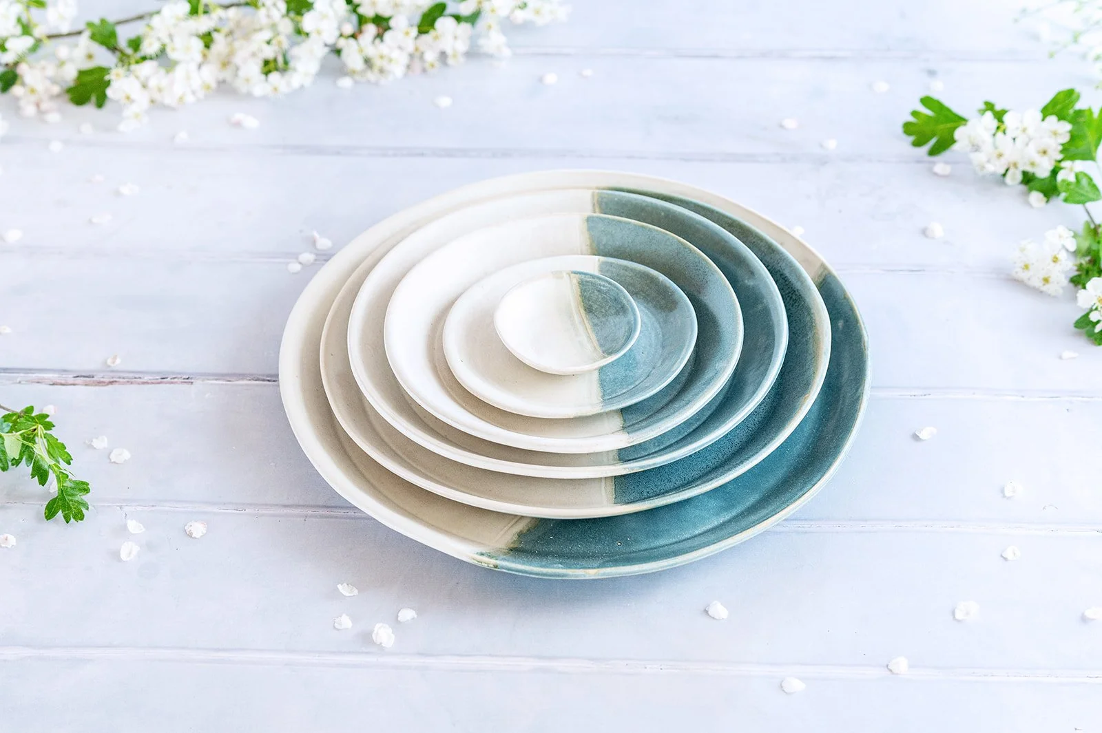 A stack of handmade SeaBlu stoneware plates in graduated sizes, sea blue and American alabaster glaze.