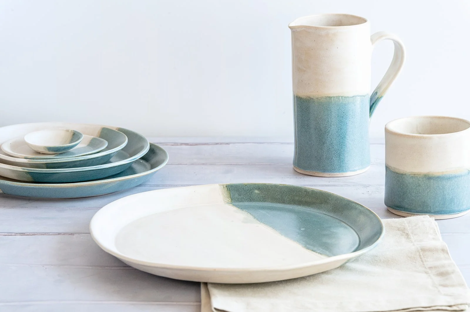 SeaBlu handmade stoneware tableware — plates, jug and mug in sea blue glaze, by Isil Ceramics.