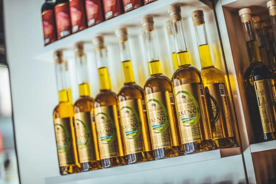 Flesjes met olie op een koelkastplank, er bovenop een rij met potten of blikken.