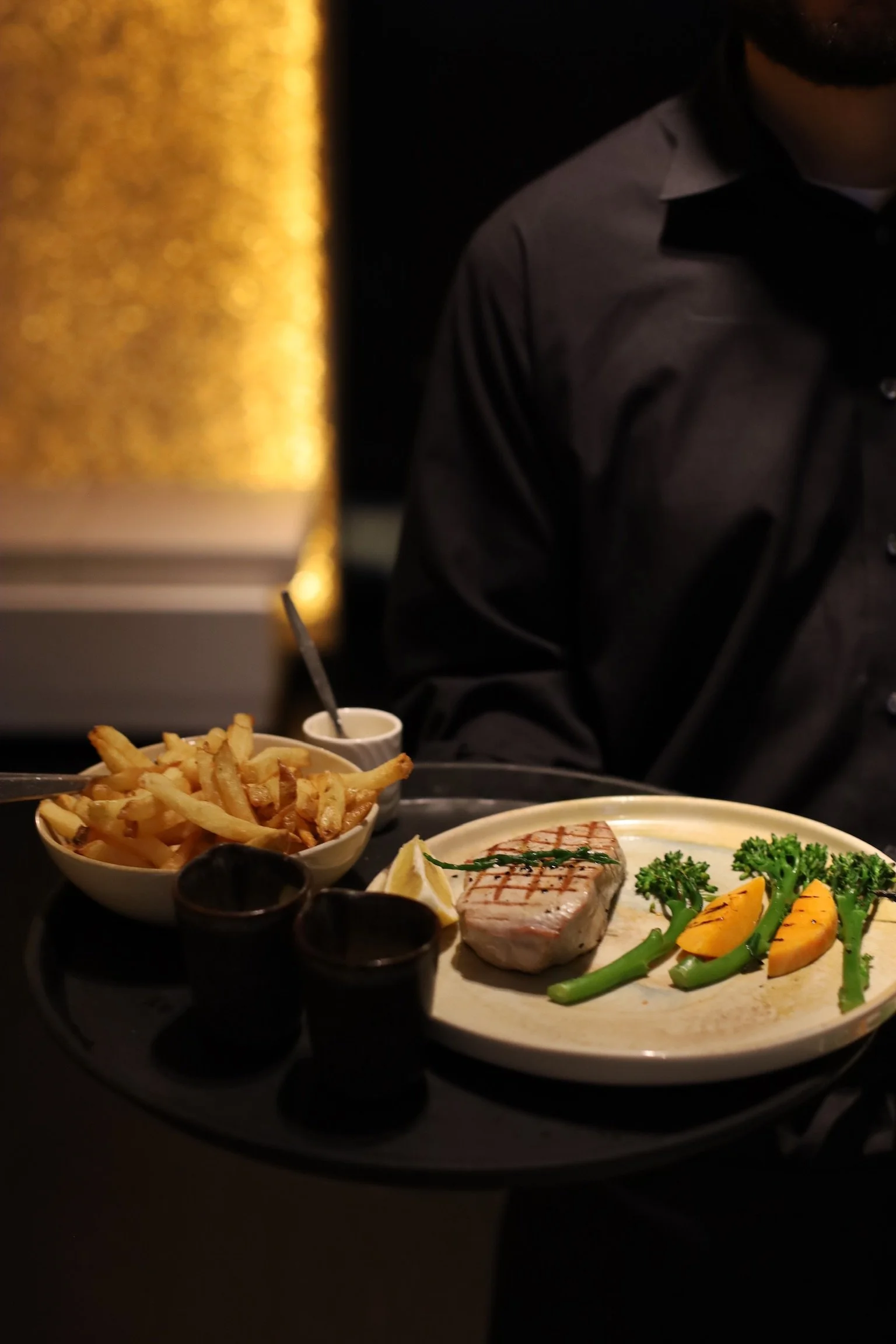 Gereserveerd bord met gegrilde tonijn, broccoli, ananas, en French fries, geserveerd in een restaurant setting.