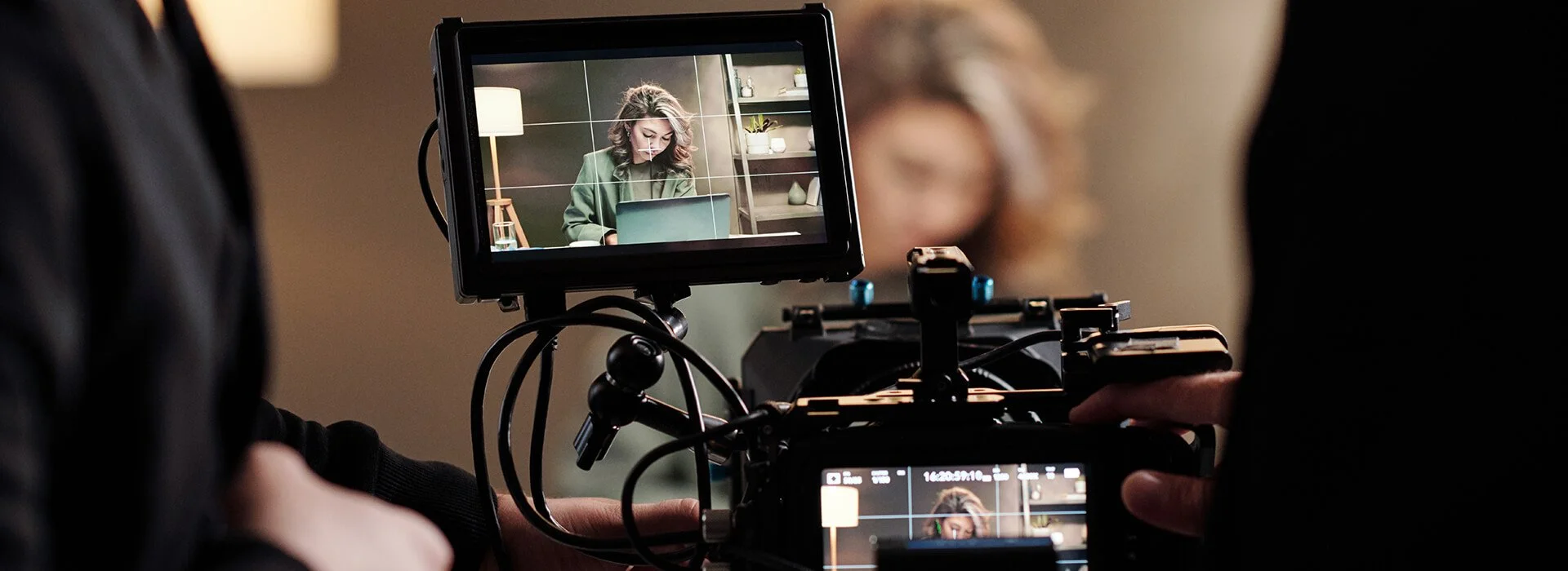 Camera operator framing a seated subject on a monitor during a small-team video shoot