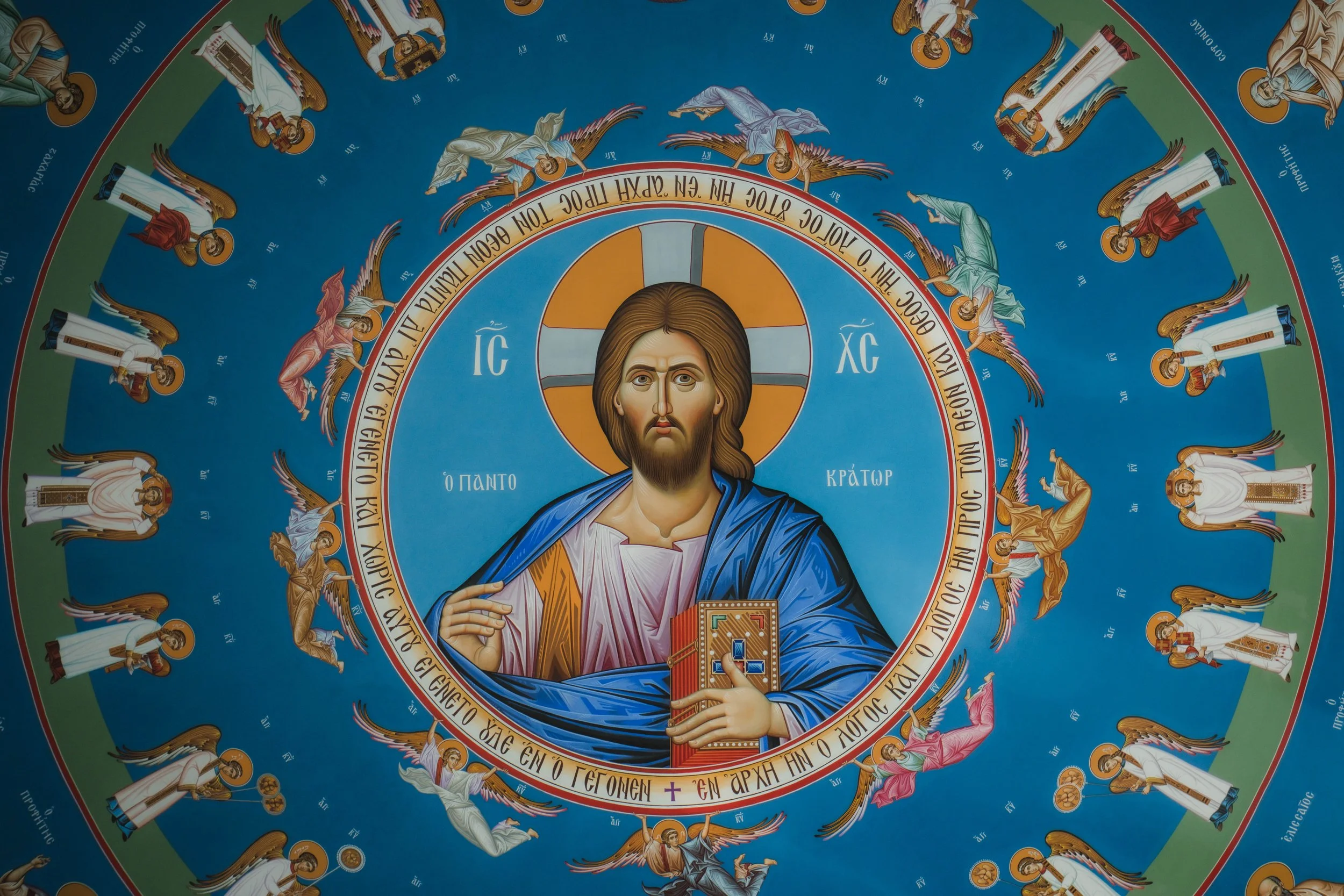 Mural of Jesus Christ with a halo and a book, surrounded by angels and Greek inscriptions.