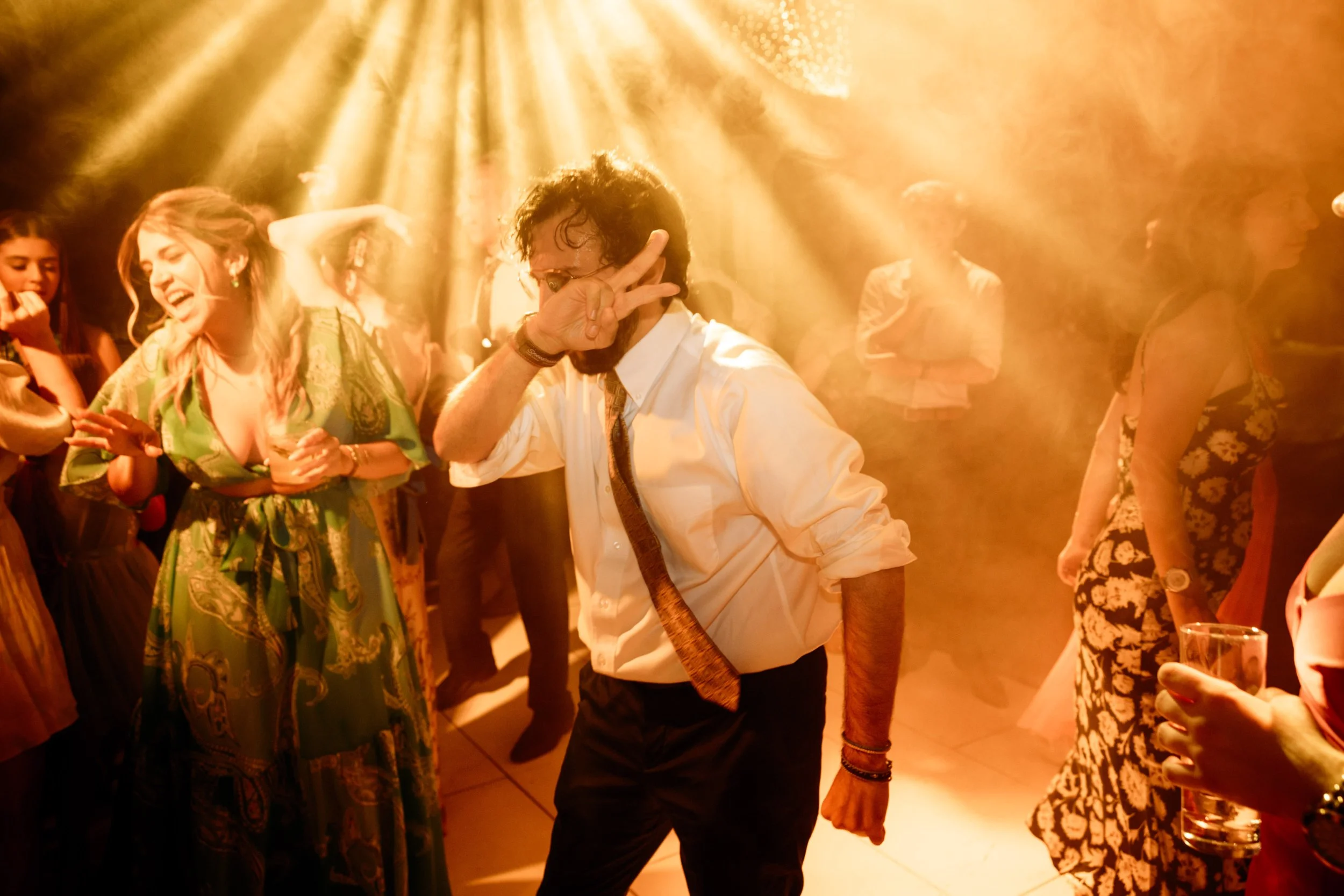 People dancing and enjoying themselves at a party with warm lighting and a lively atmosphere.