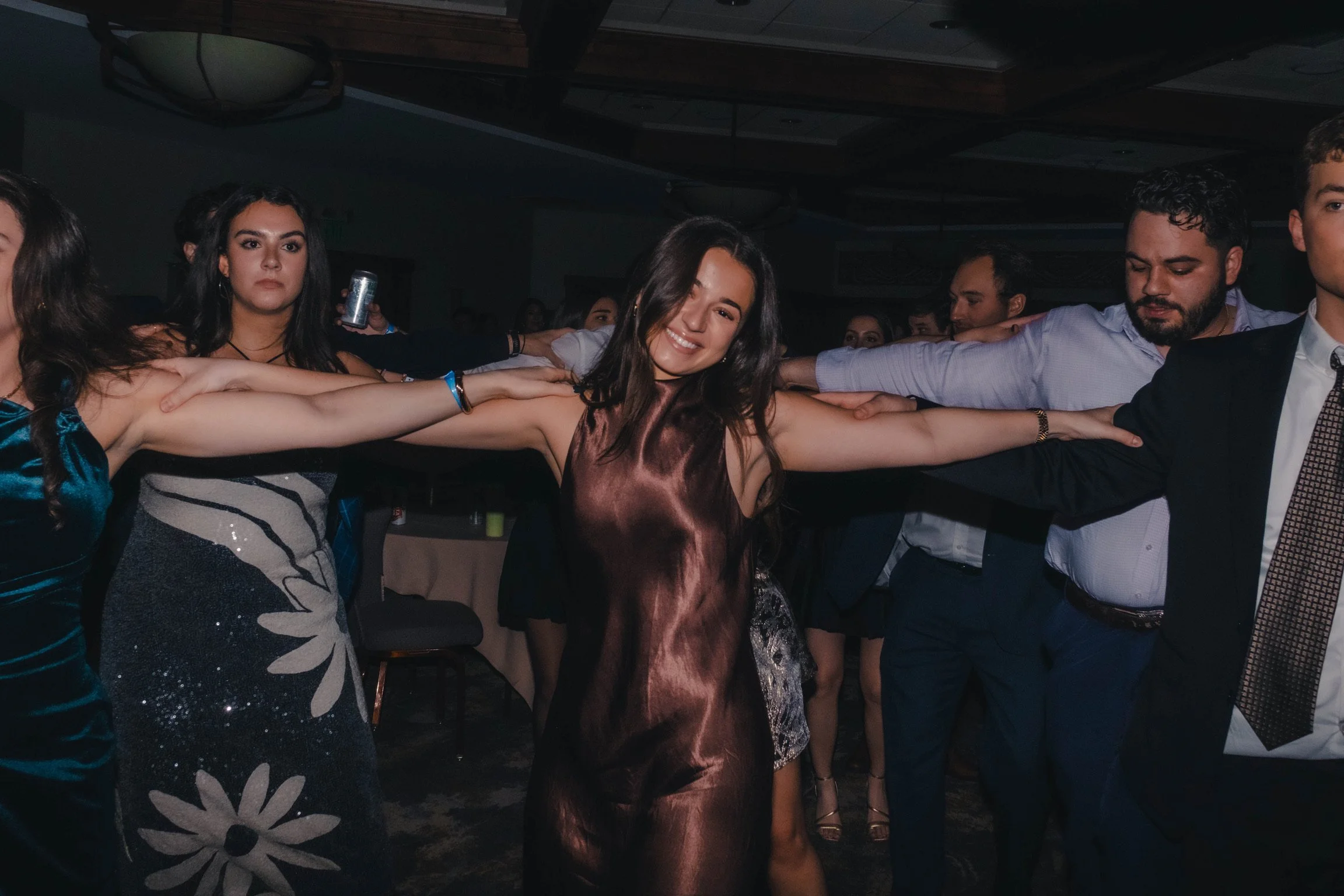 Group of young people dancing in a conga line at a party or celebration.