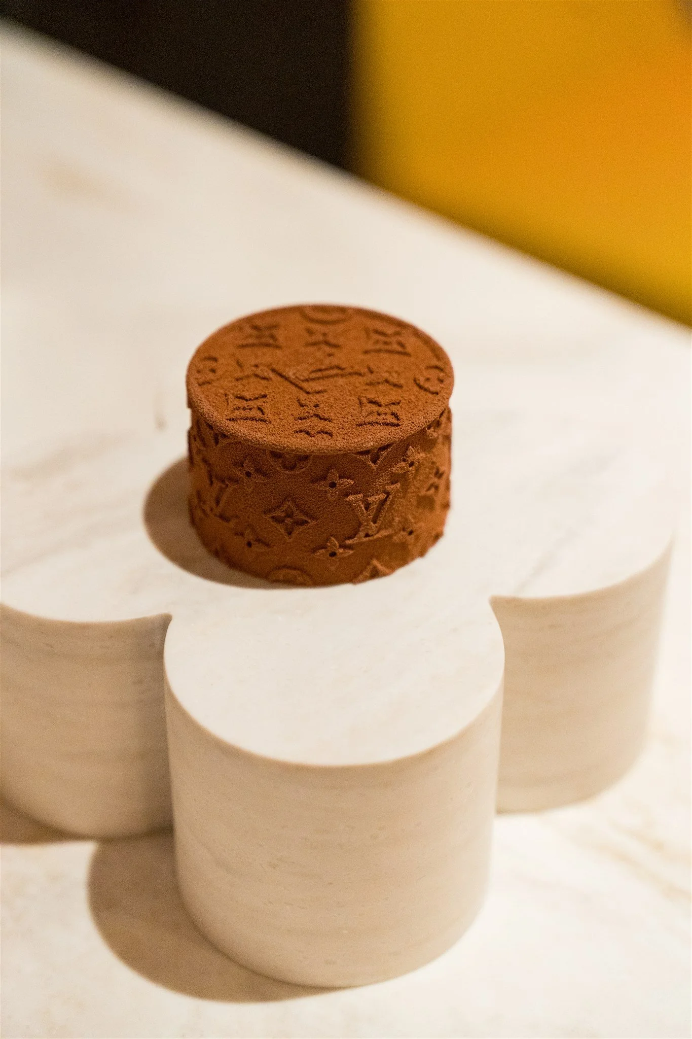 Close-up of a round, textured, brown object with engraved patterns, resting on a white, flower-shaped stand.