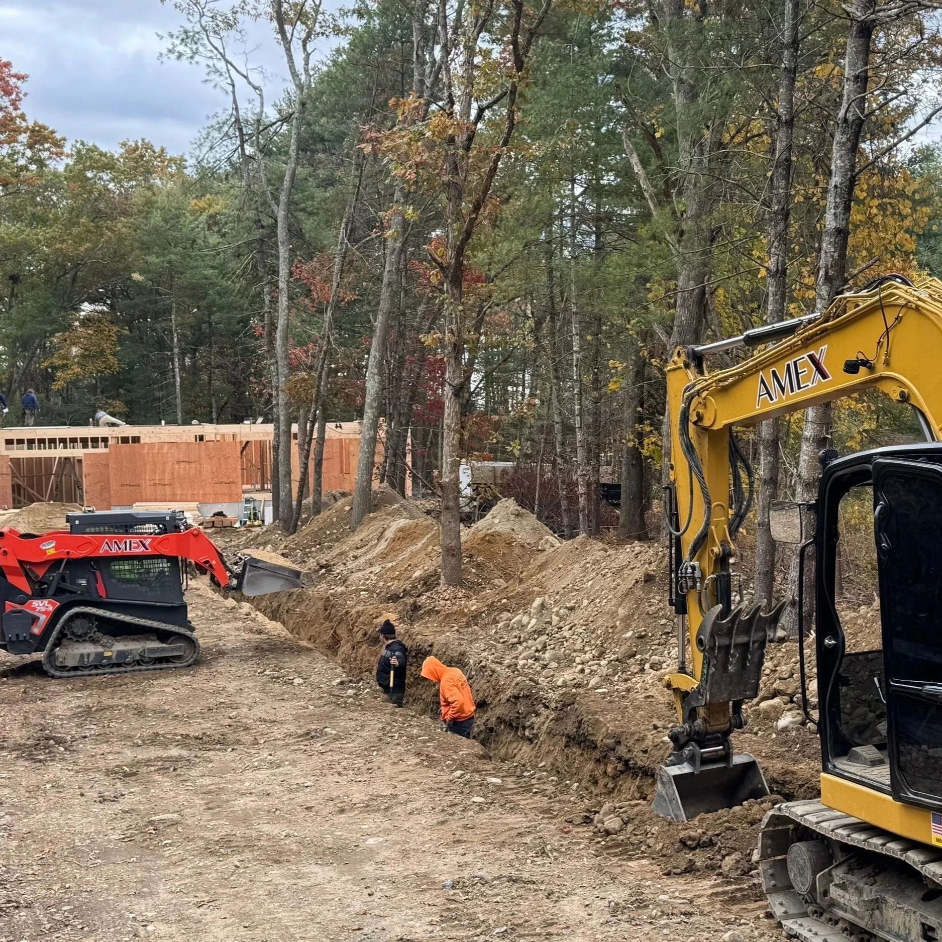 Construction site with heavy machinery and worker leveling the ground for a building foundation.