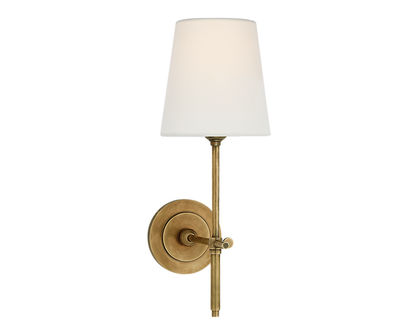 Wall-mounted brass lamp with a white lampshade.