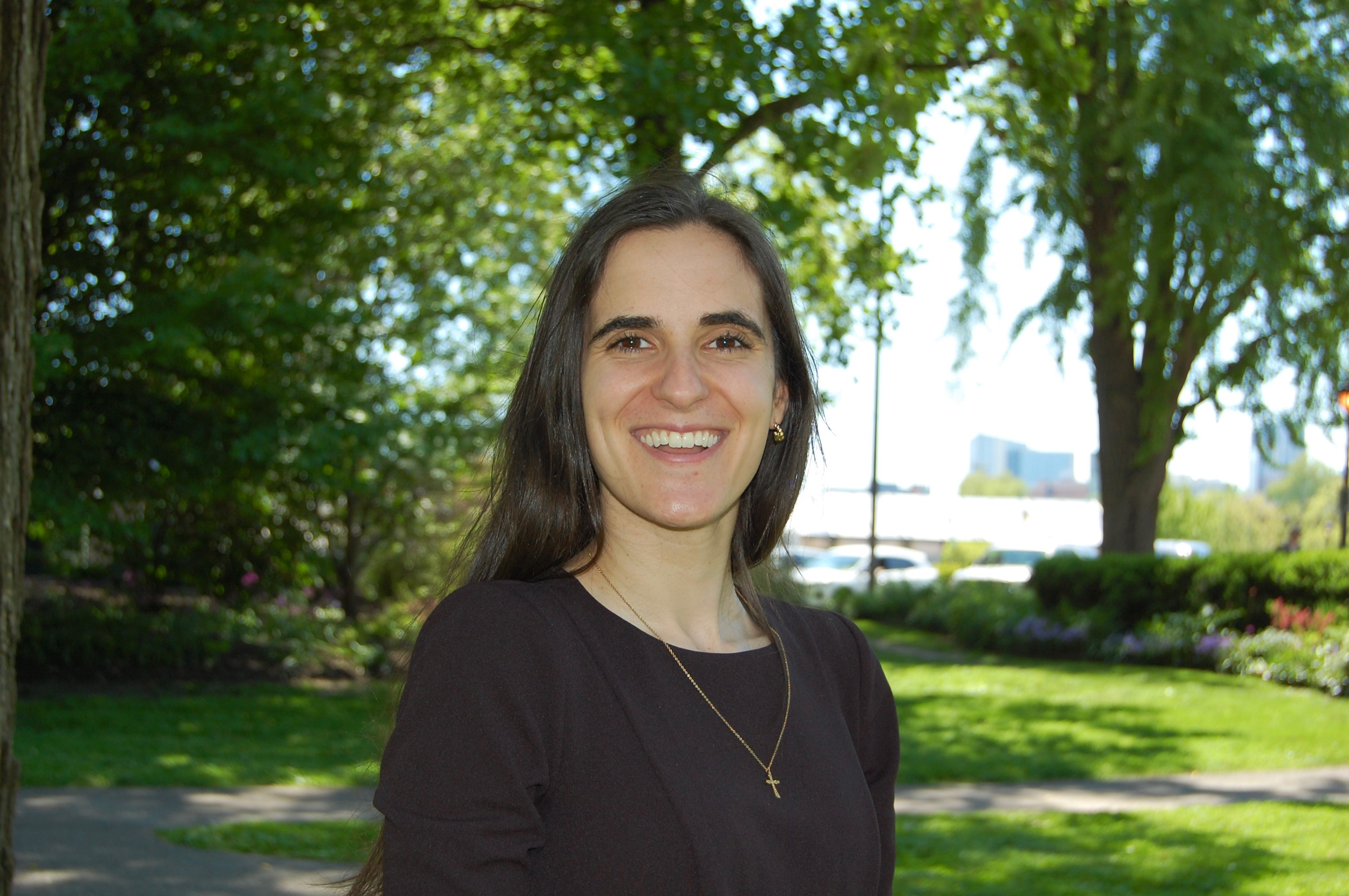 Woman smiling outdoors with trees in the background