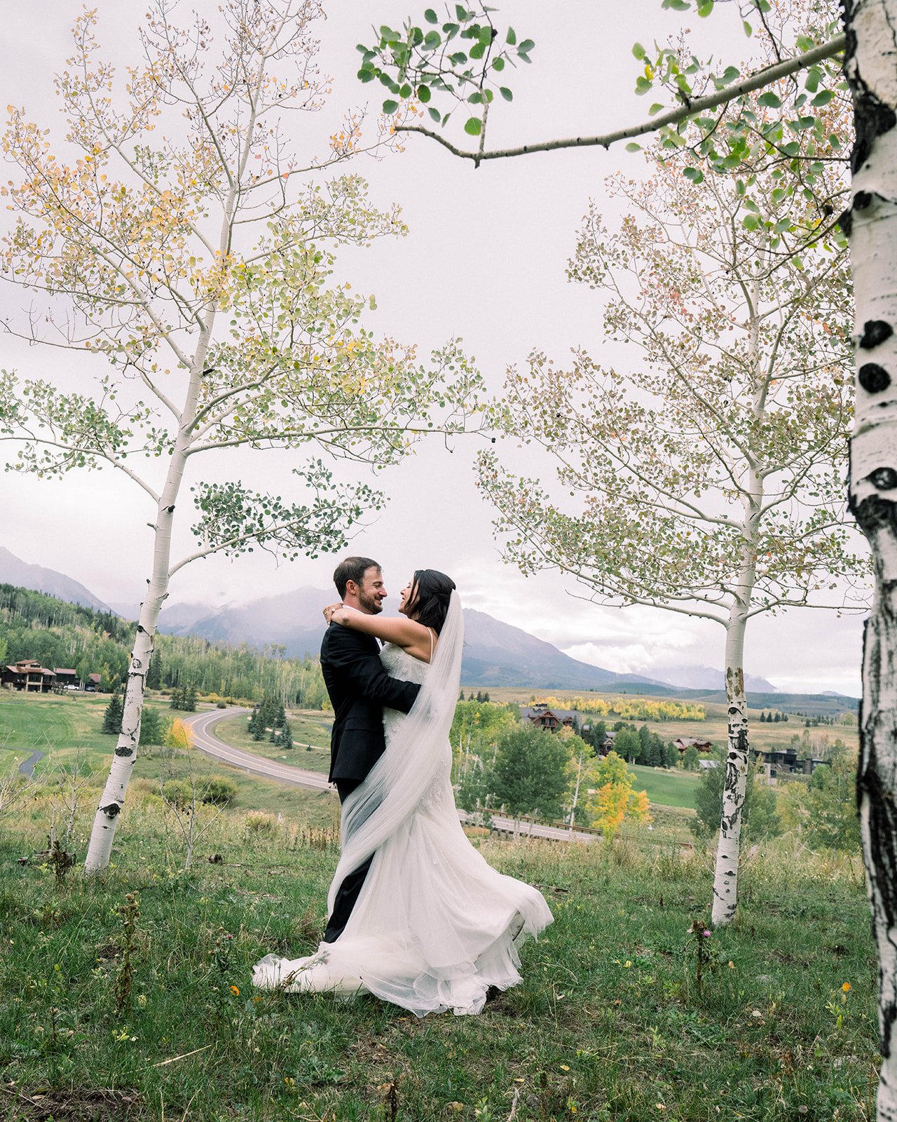 A bride and groom sharing a kiss during their wedding, surrounded by flowers.
