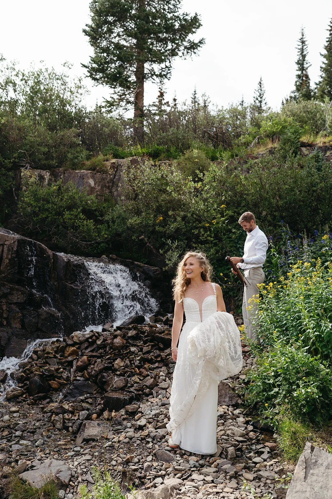 Couple smiles near waterfall on wedding day