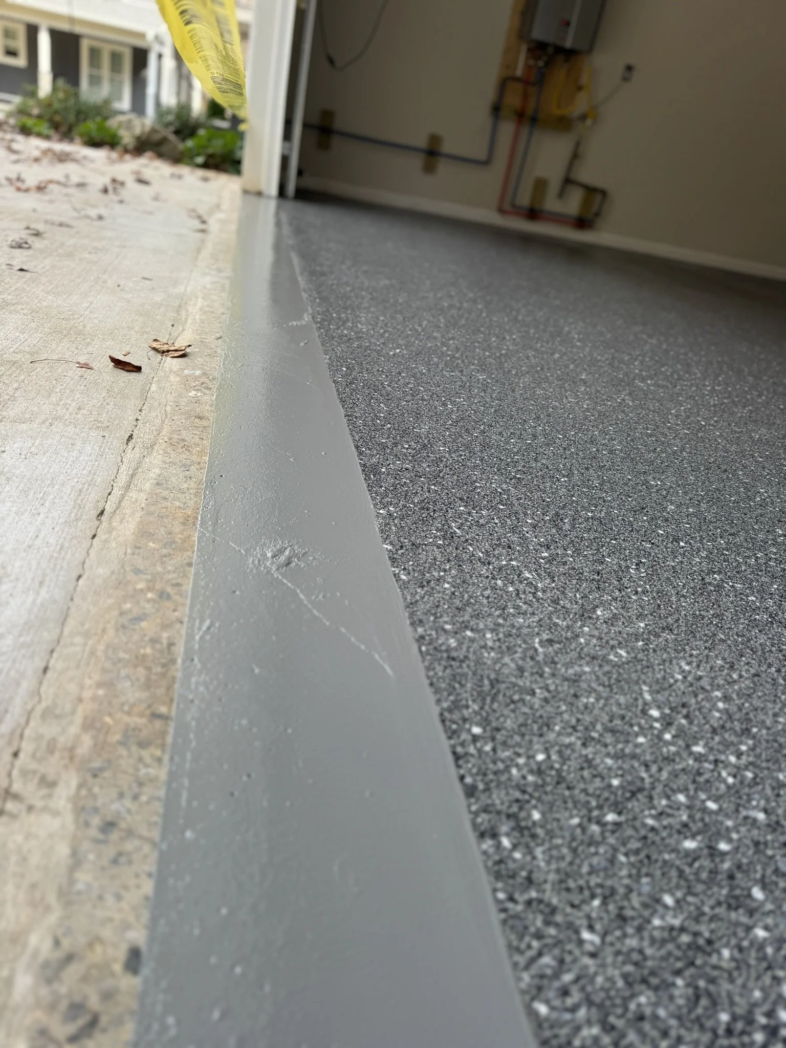 Empty garage with custom epoxy flake flooring and grey sealer on the apron of the garage