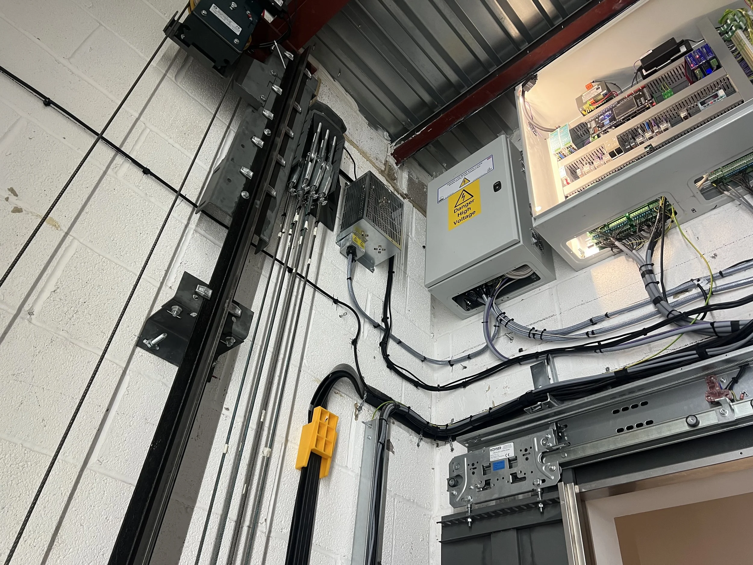 The top of a lift shaft, with controller, gearbox and ropes on show.