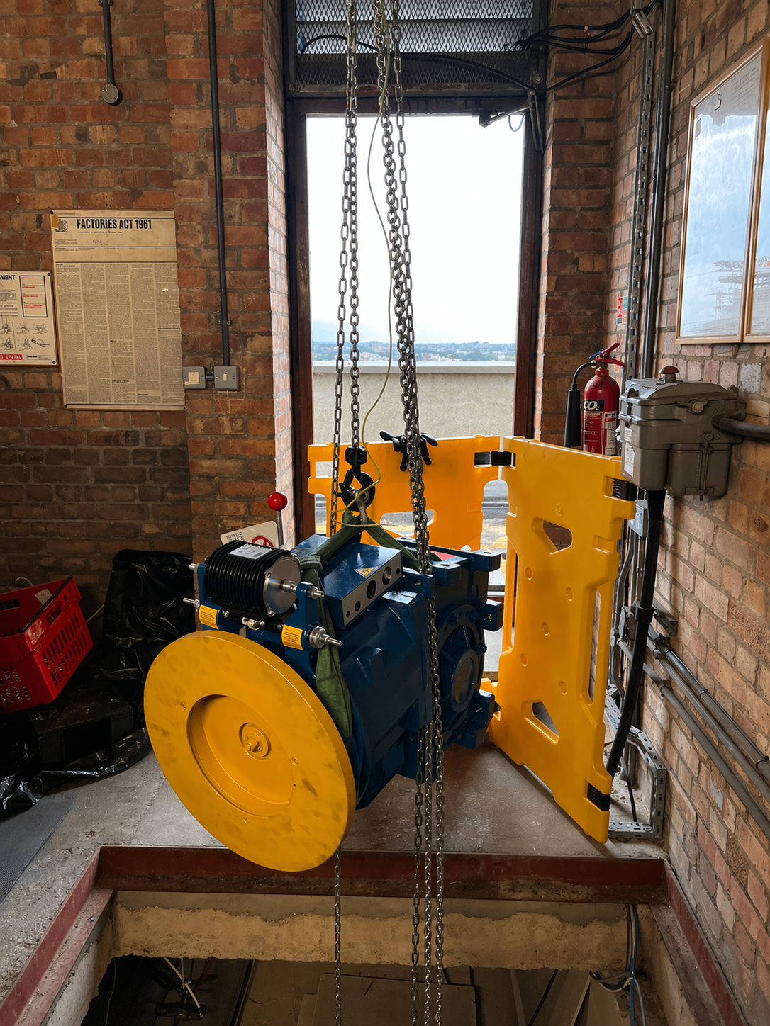 A motor and gearbox for a lift, being hoisted into the motor room by a tackle.