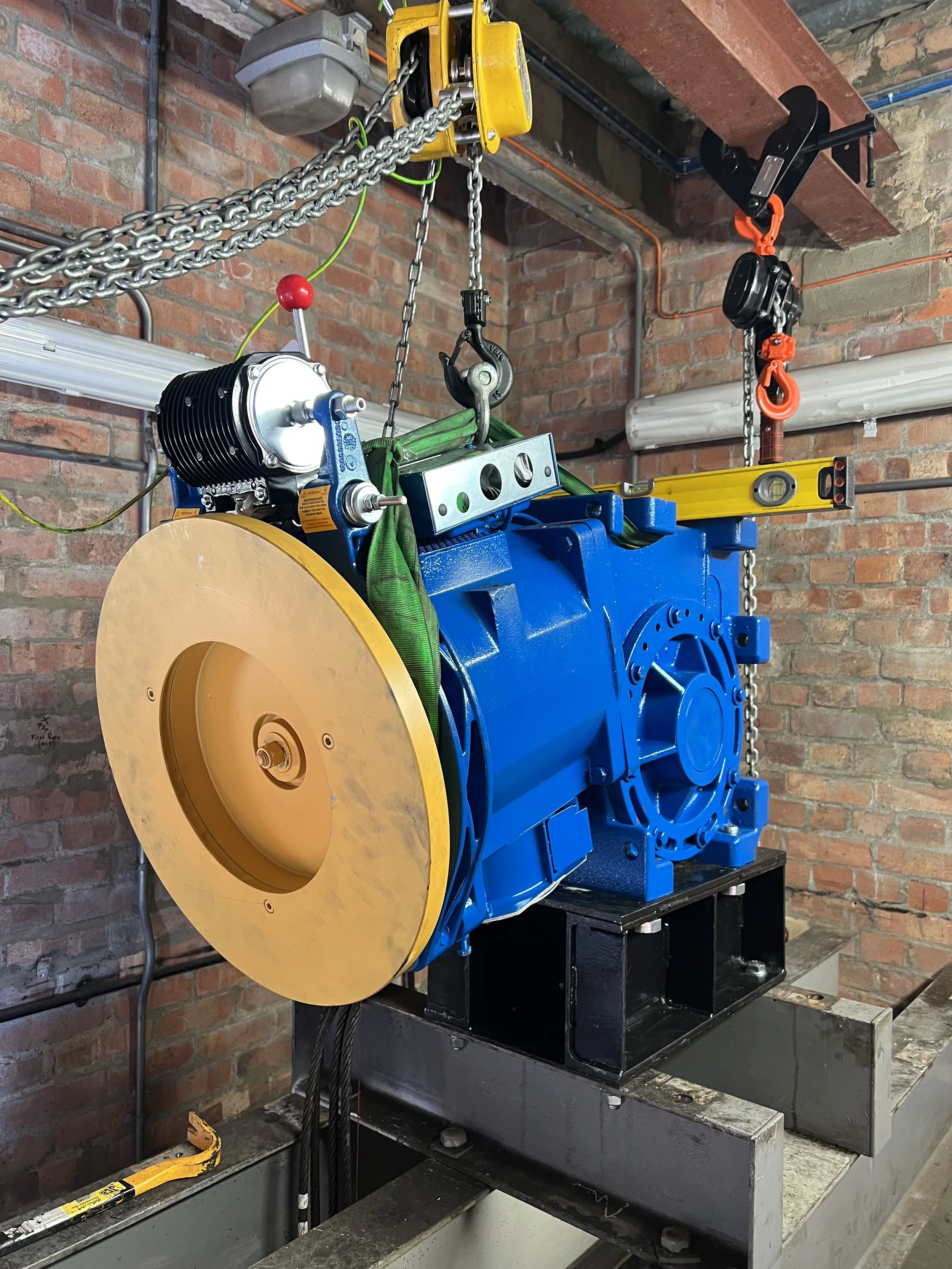 A motor and gearbox for a lift, hoisted up by a tackle.
