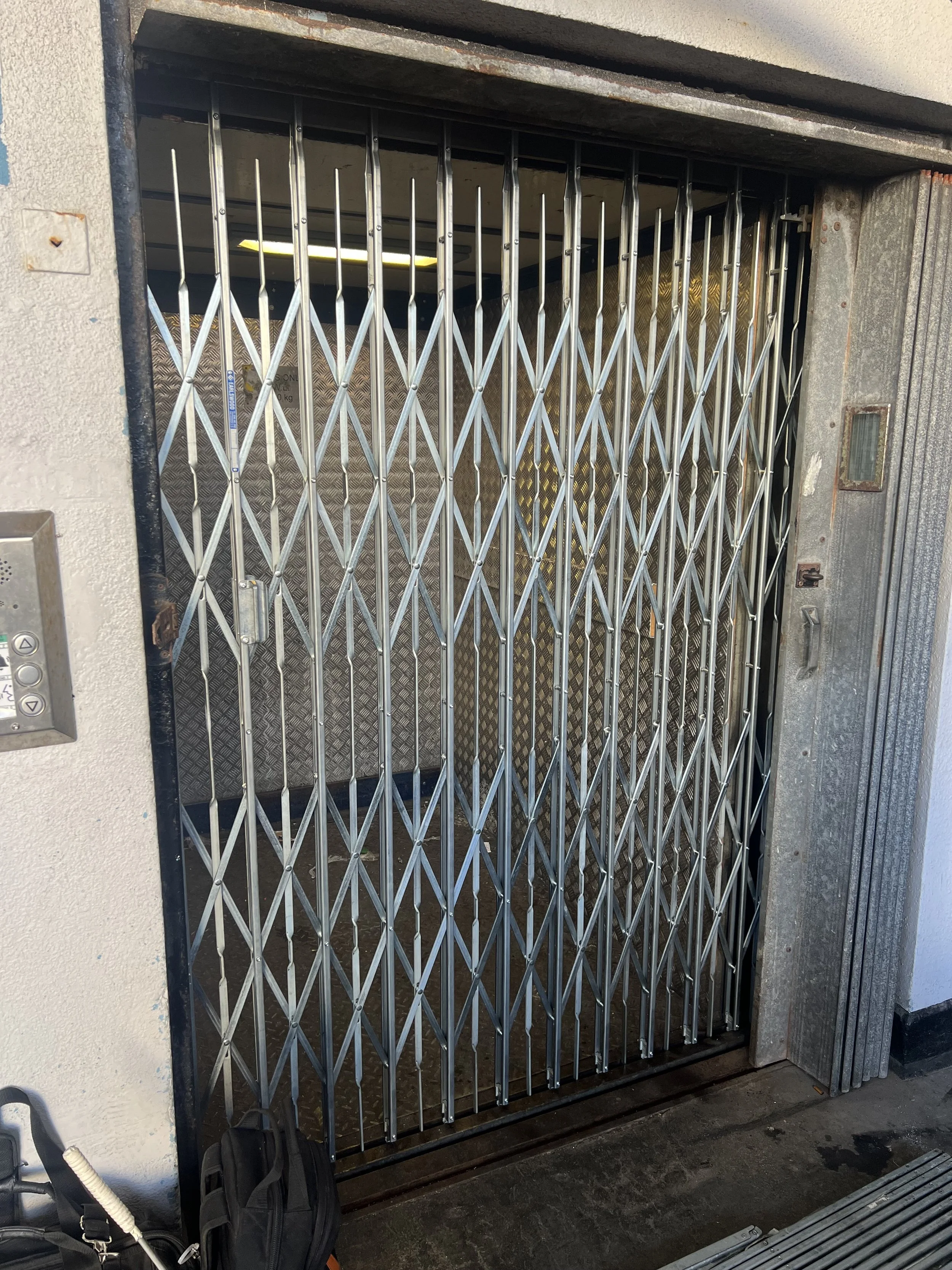 A brand new, freshly installed latice-style gate for a goods lift.