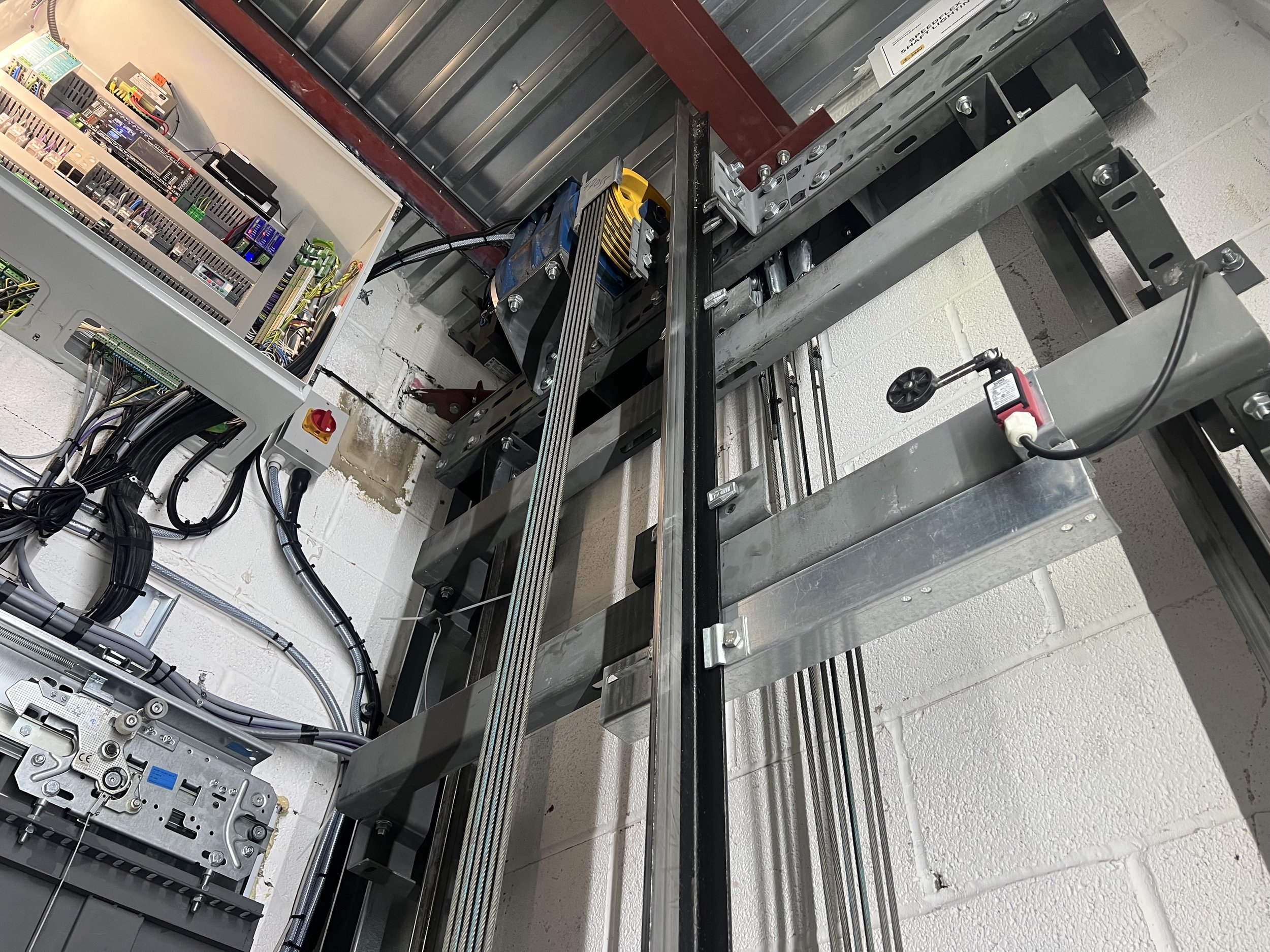 The top of a lift shaft, with controller, gearbox and ropes on show.