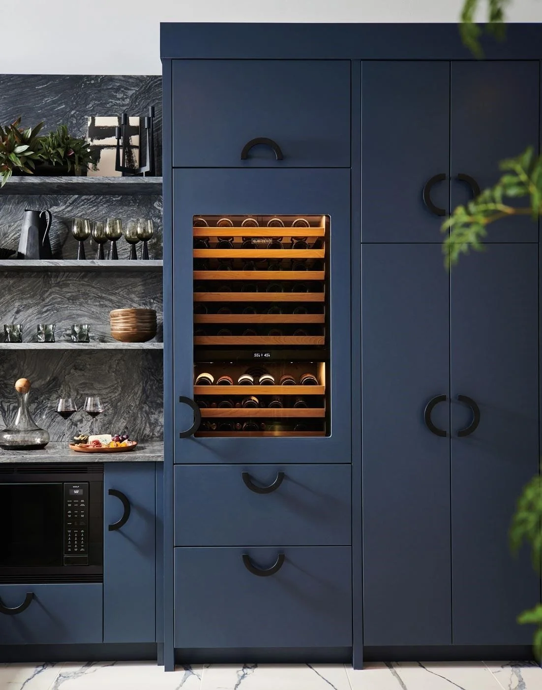 Two kitchen wine refrigerators, one blue and one stainless steel, built into cabinetry, with wine racks visible through glass doors.