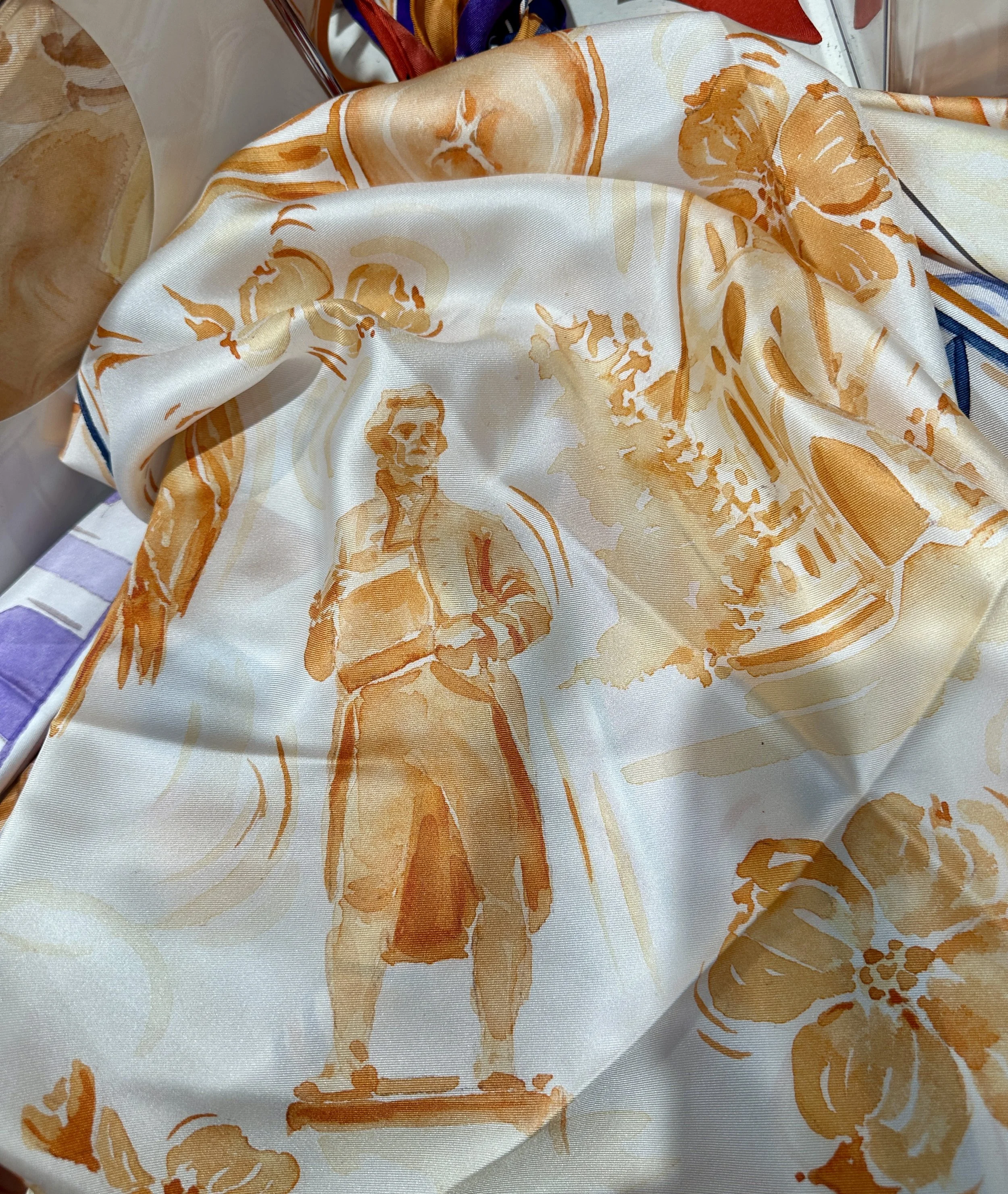 UVA watercolor silk scarf by Megan Grinder, shown on the diamond, with the Rotunda and dogwood blossoms in orange inside a navy diamond border