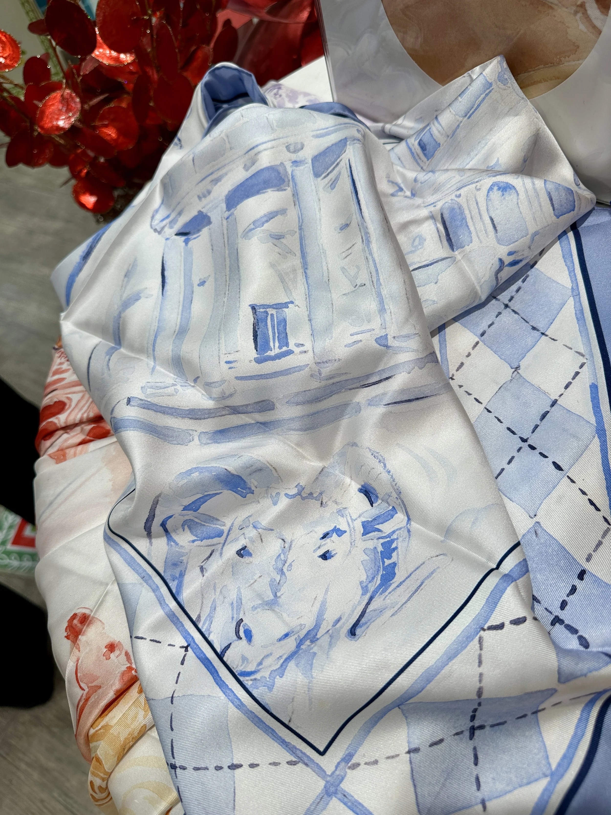 UNC watercolor silk scarf by Megan Grinder, shown on the diamond, with the Old Well and Rameses in Carolina blue inside an argyle border